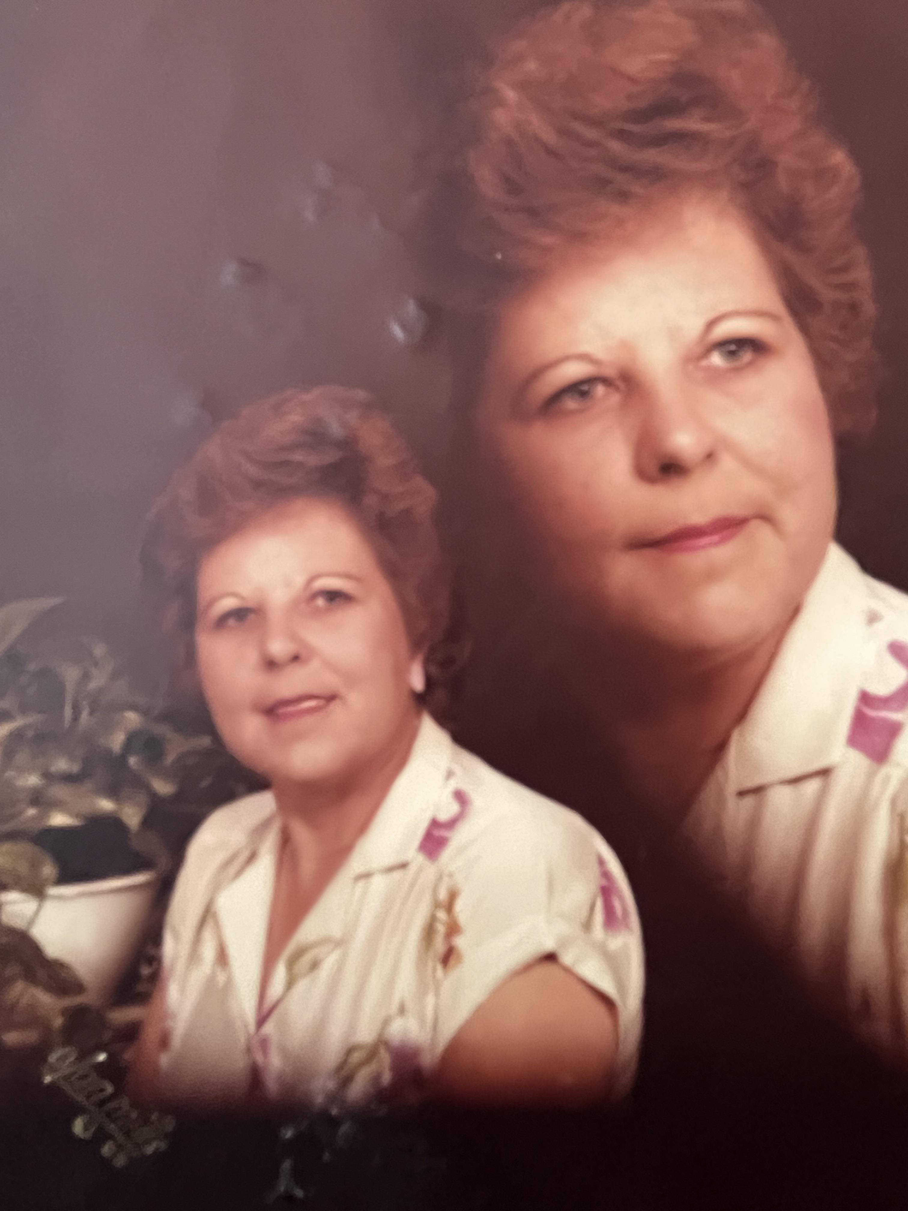 A woman with styled short hair poses at home, surrounded by greenery, radiating warmth.