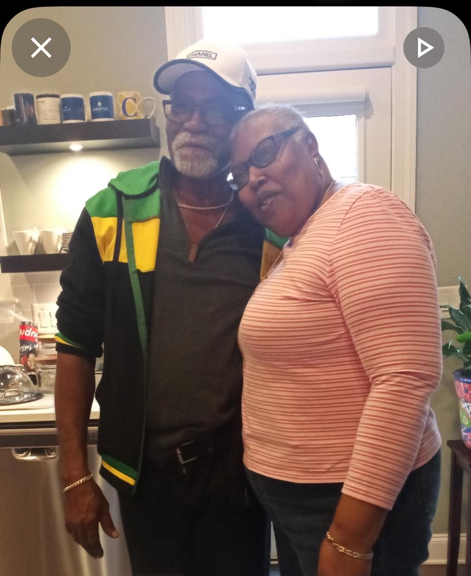 Two friends embrace happily in a well-lit kitchen, surrounded by cheerful decor and dishes.