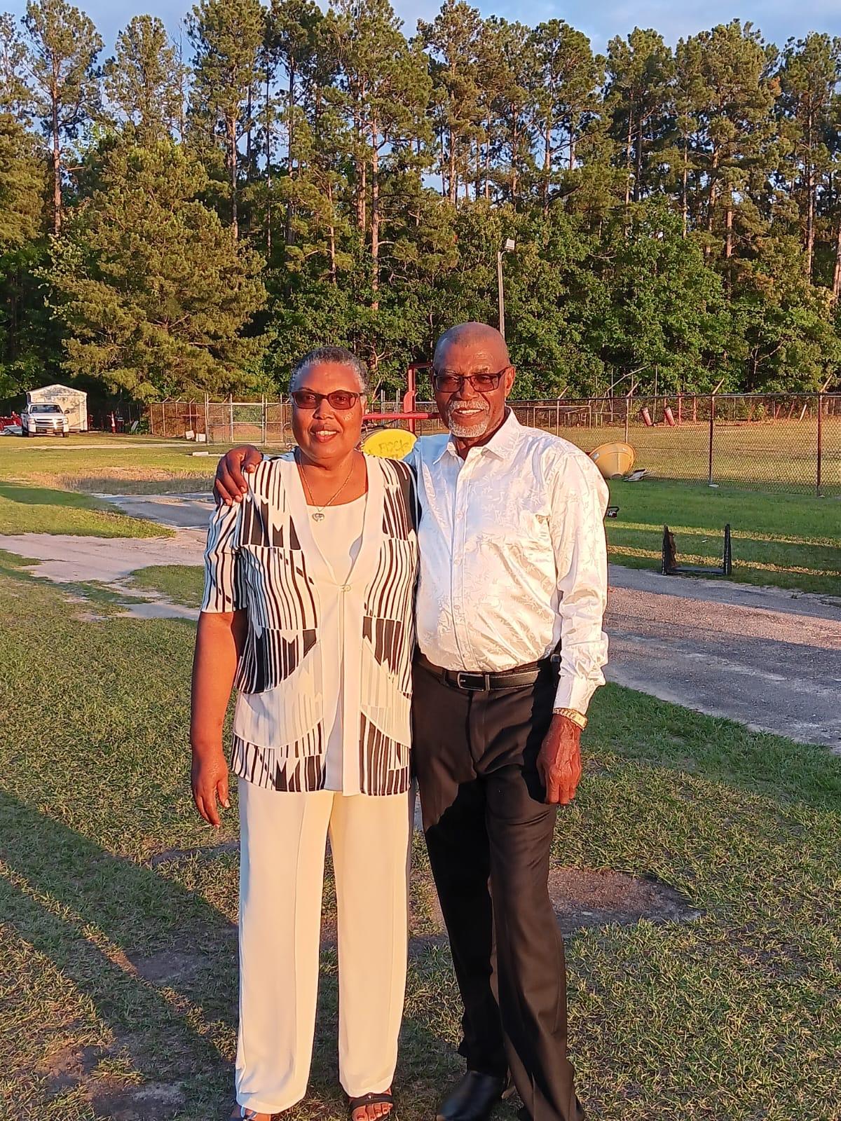 Two friends pose together in a lush green park during golden hour, celebrating a joyful moment.