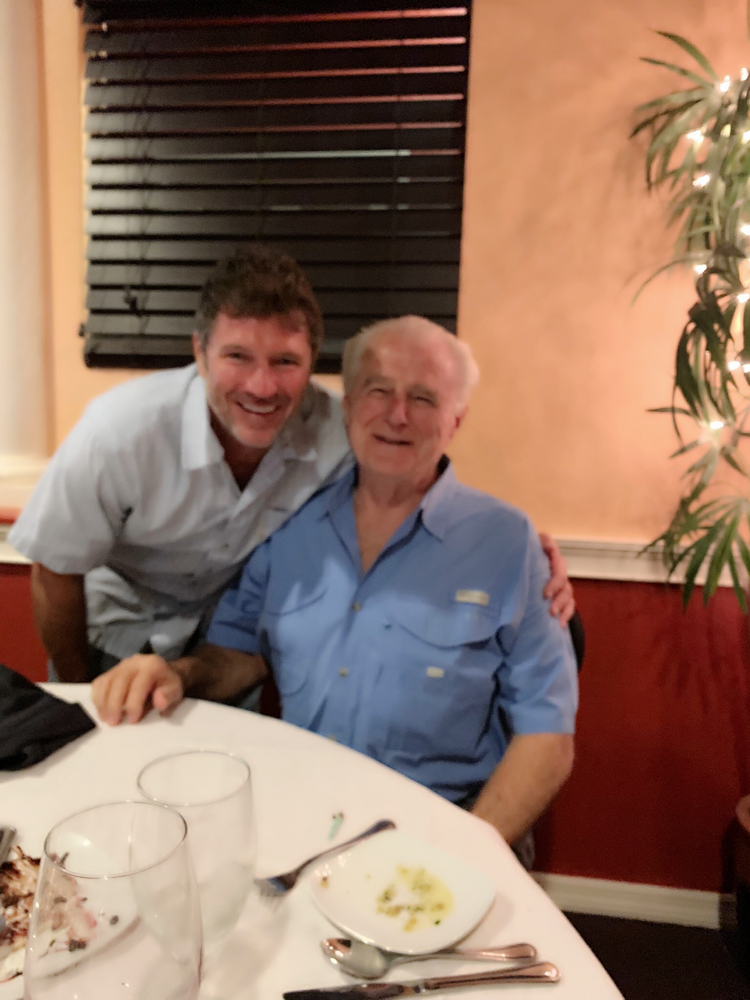 Two men share a joyful moment while dining at a charming restaurant in the evening.
