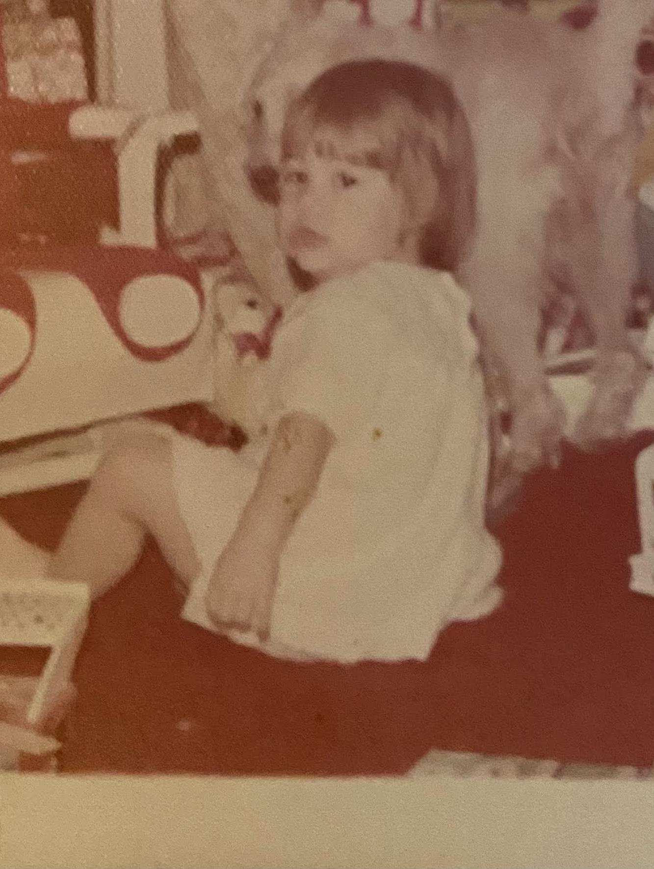A young child sits on the floor, engaged with colorful toys in a cozy living room.