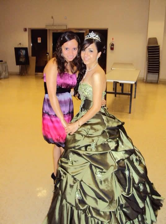 Two young girls enjoy a joyful moment in elegant dresses during a celebration in a hall.