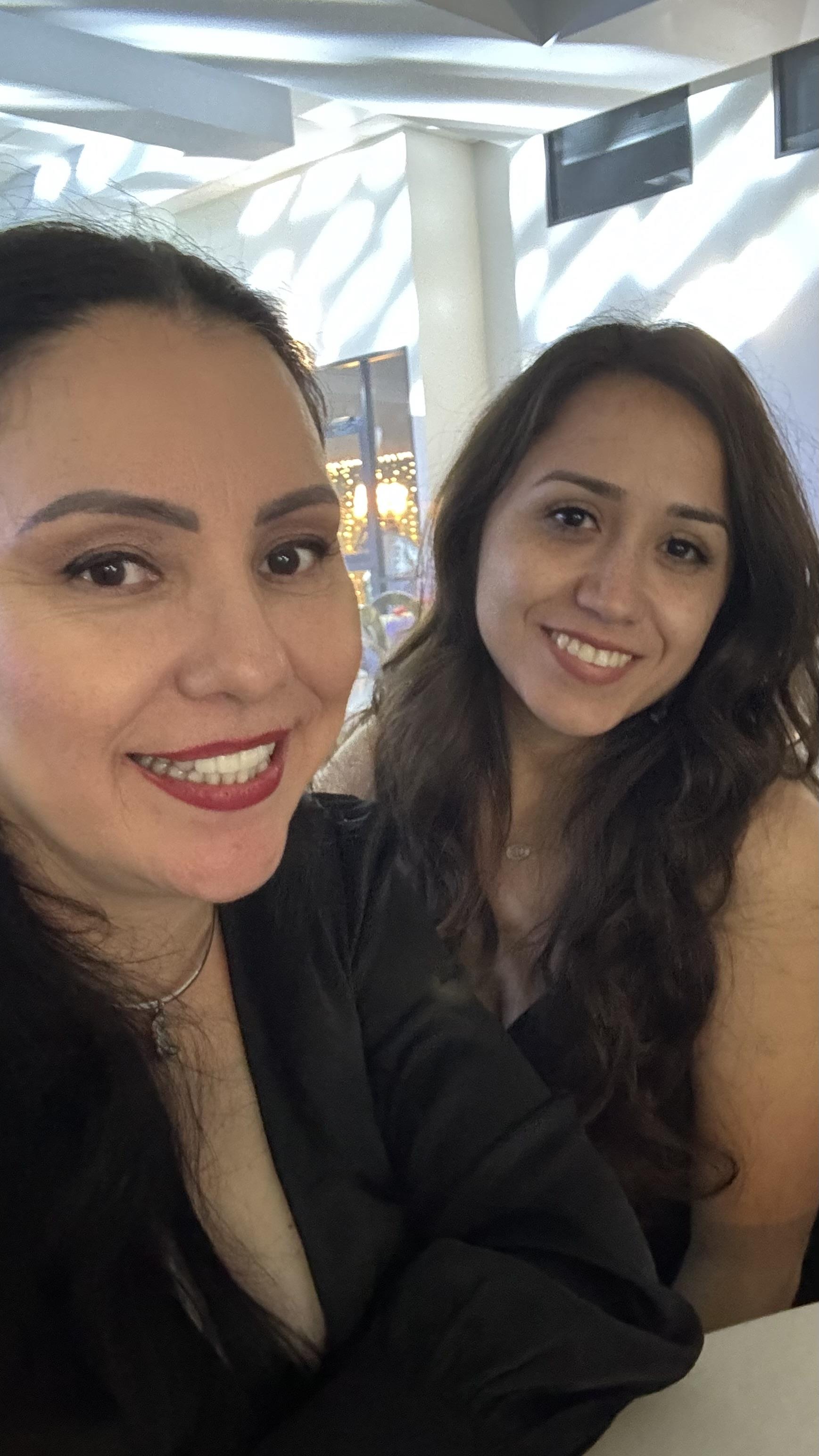 Two women at a cafe share smiles and joy while enjoying their day together.