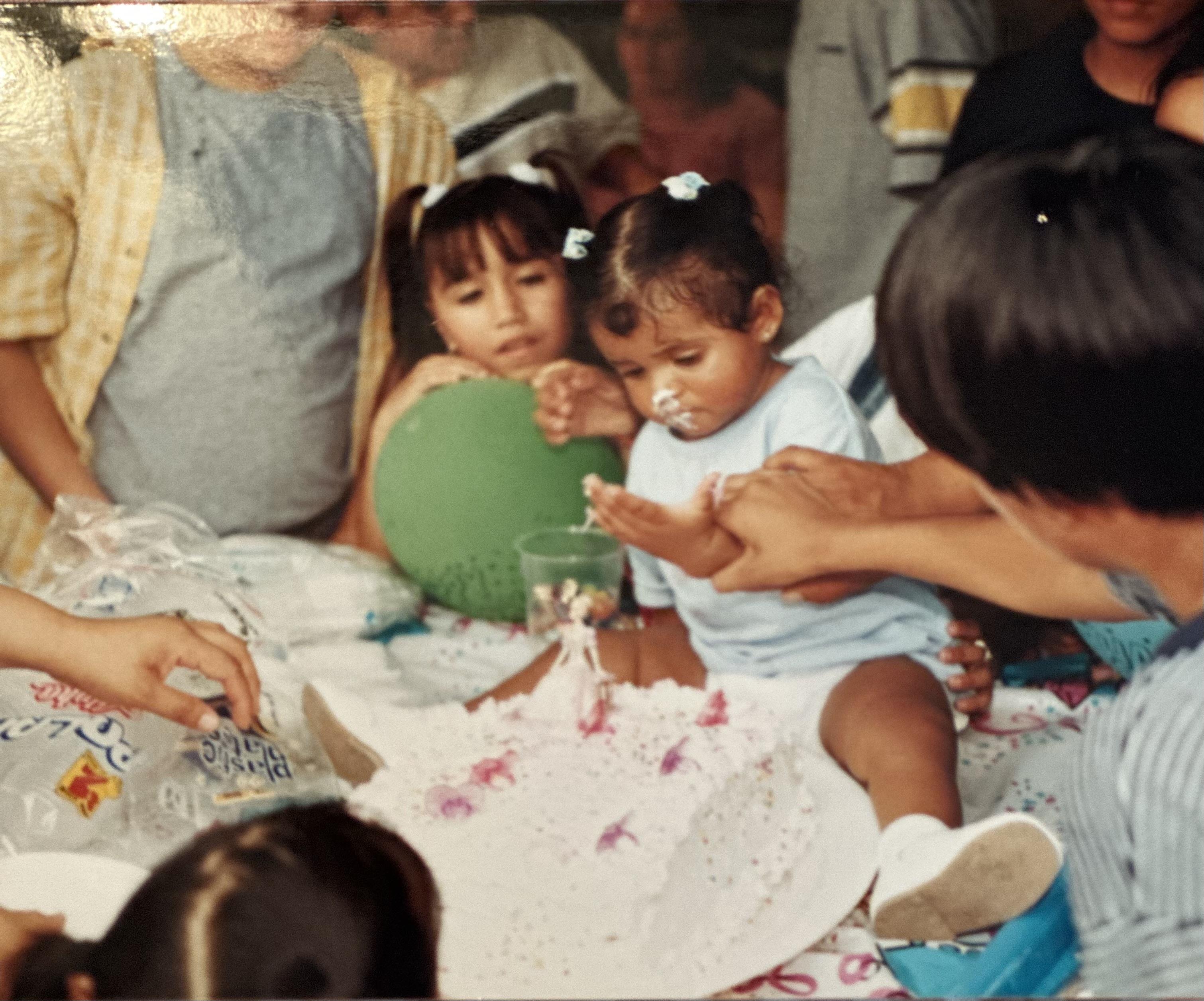 A young child enjoys cake while family members gather around, celebrating a special birthday moment.