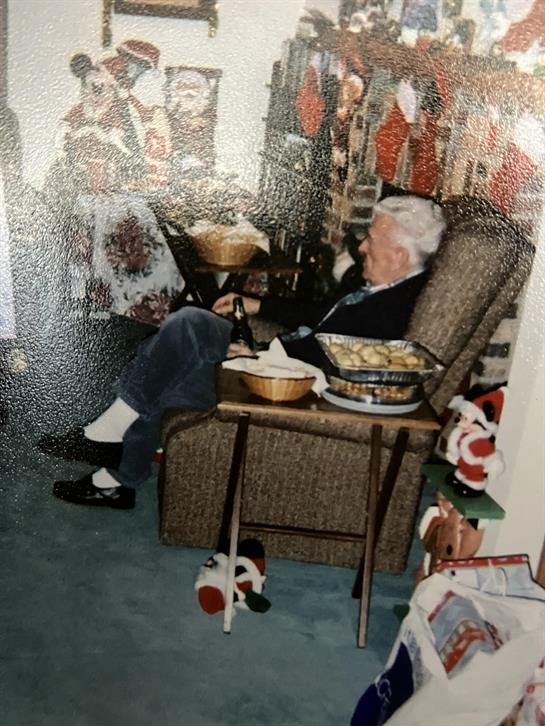 An old man sitting in a chair with food on a table