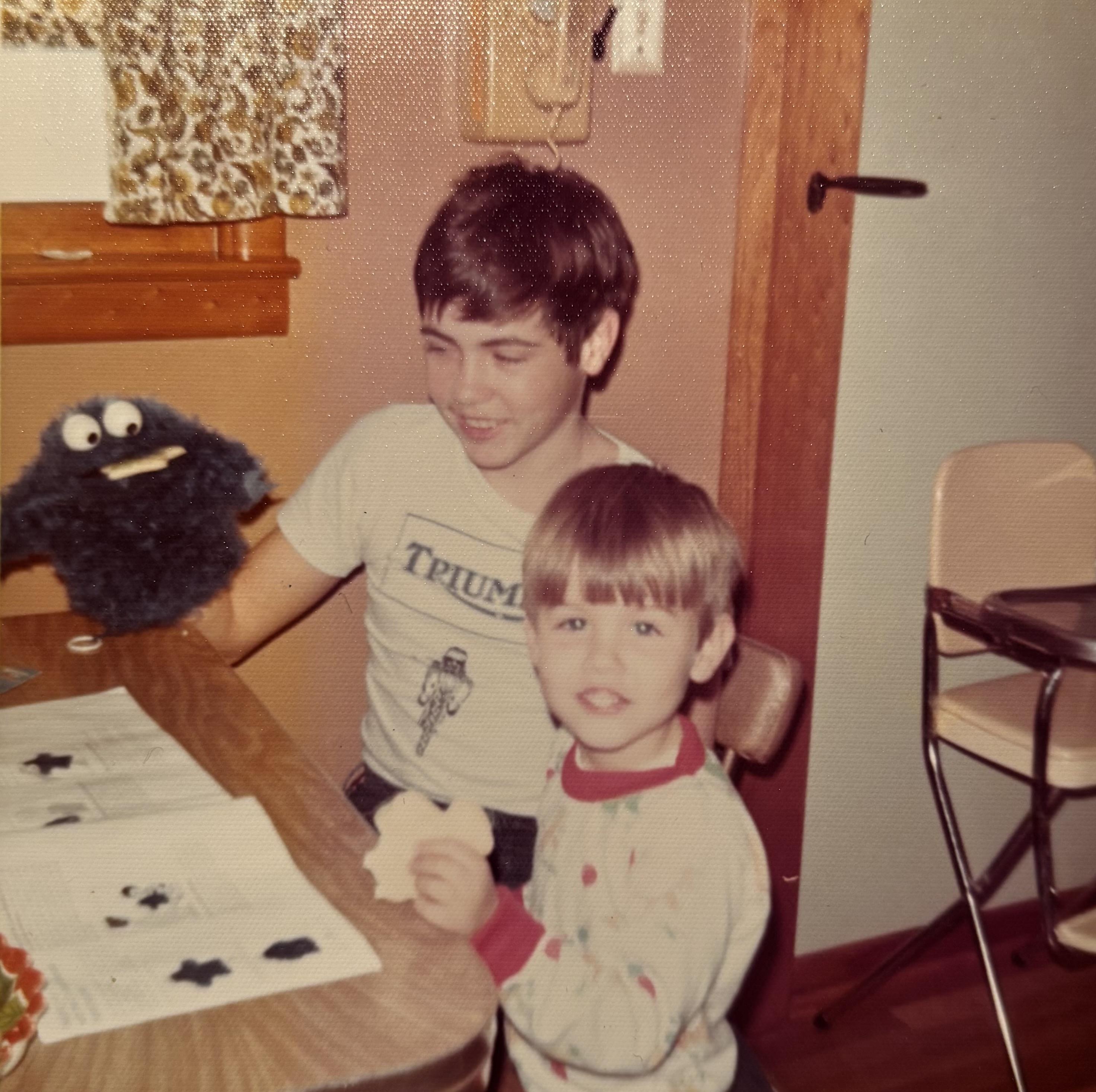 Child enjoys playing with a puppet alongside an adult in a cozy indoor space, laughing and engaging.