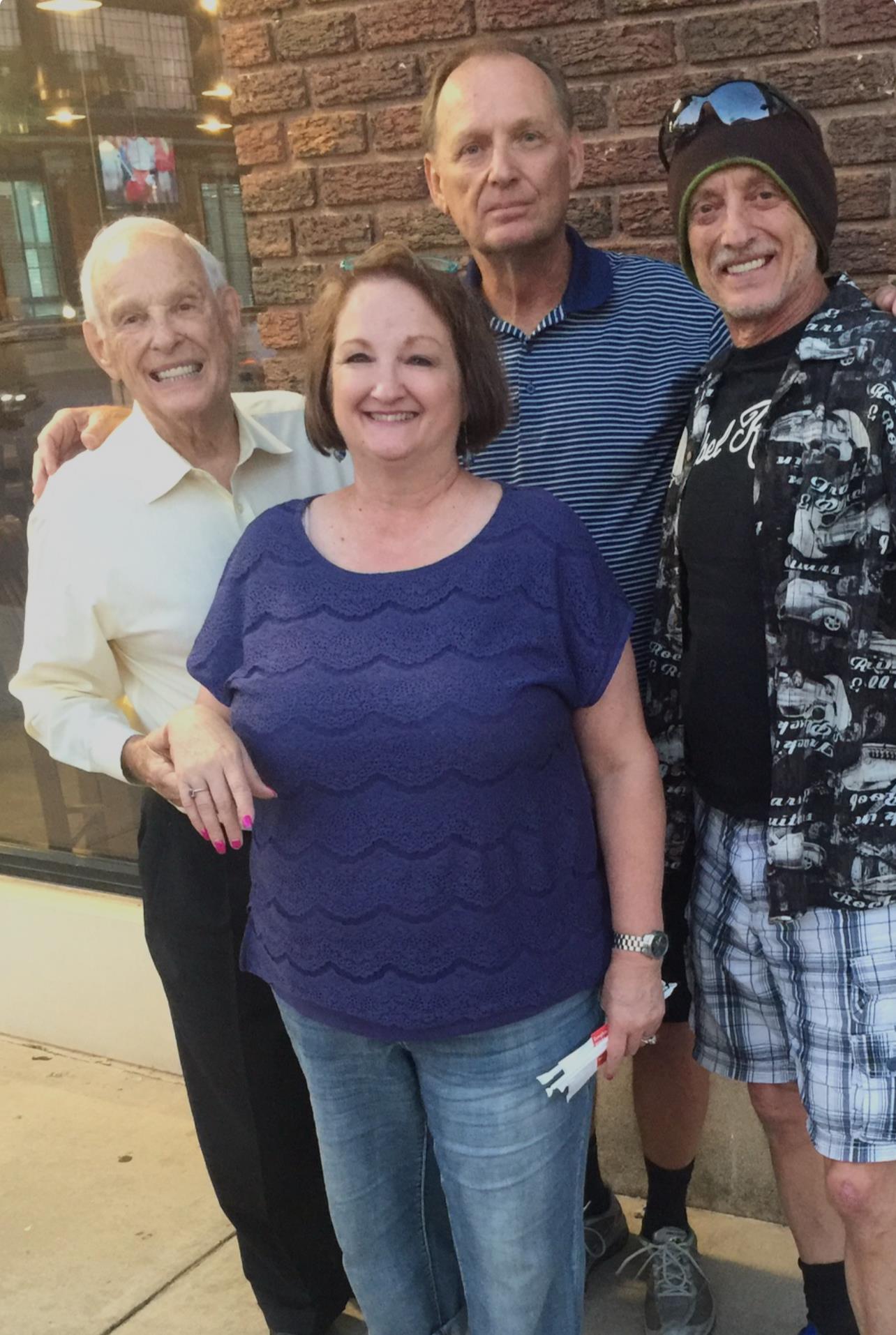 Four friends gather joyfully outside a restaurant, sharing smiles and good memories.