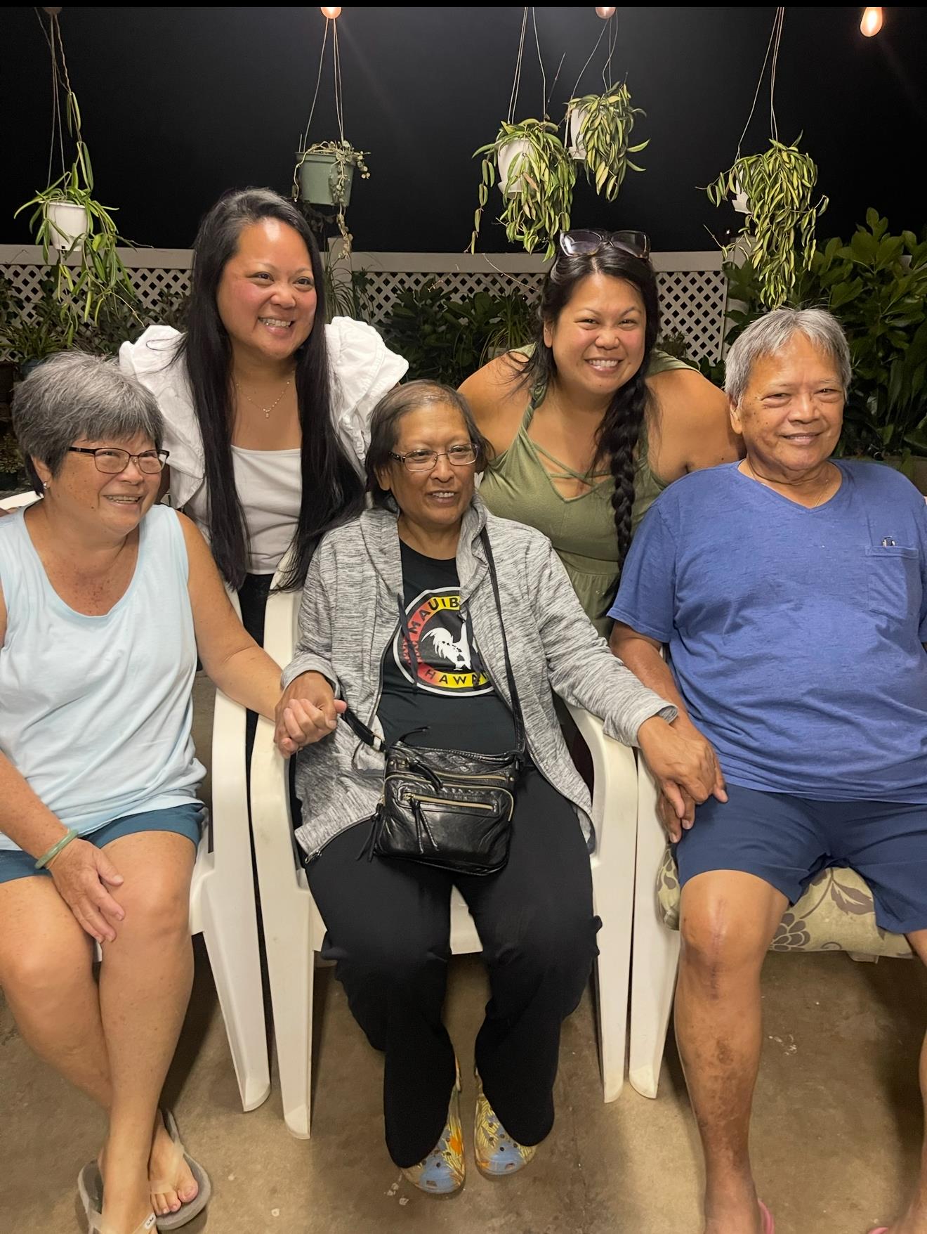 Four individuals sit together smiling warmly in an inviting indoor space surrounded by plants.
