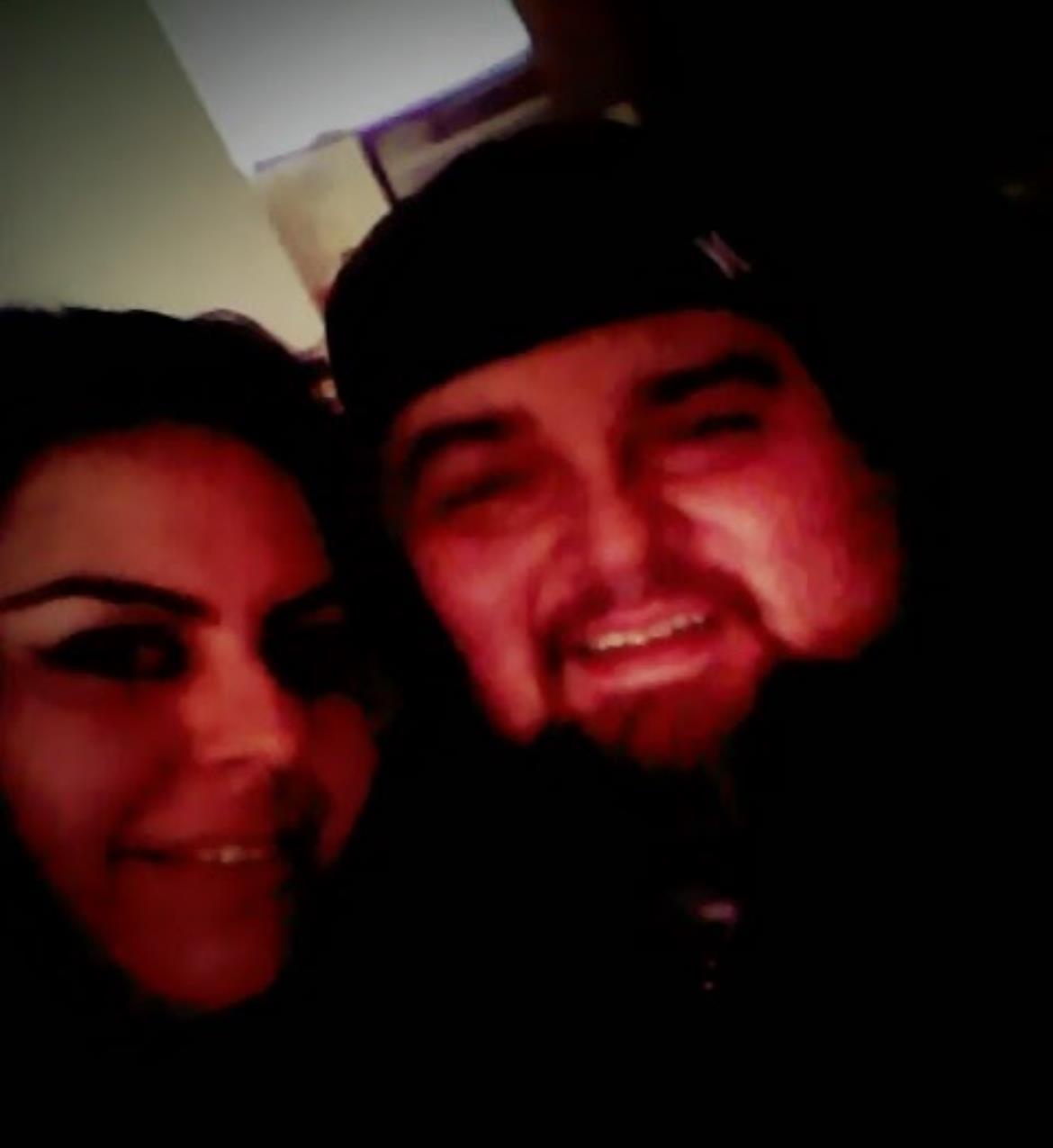 Two people share a joyful smile while posing closely in low light.