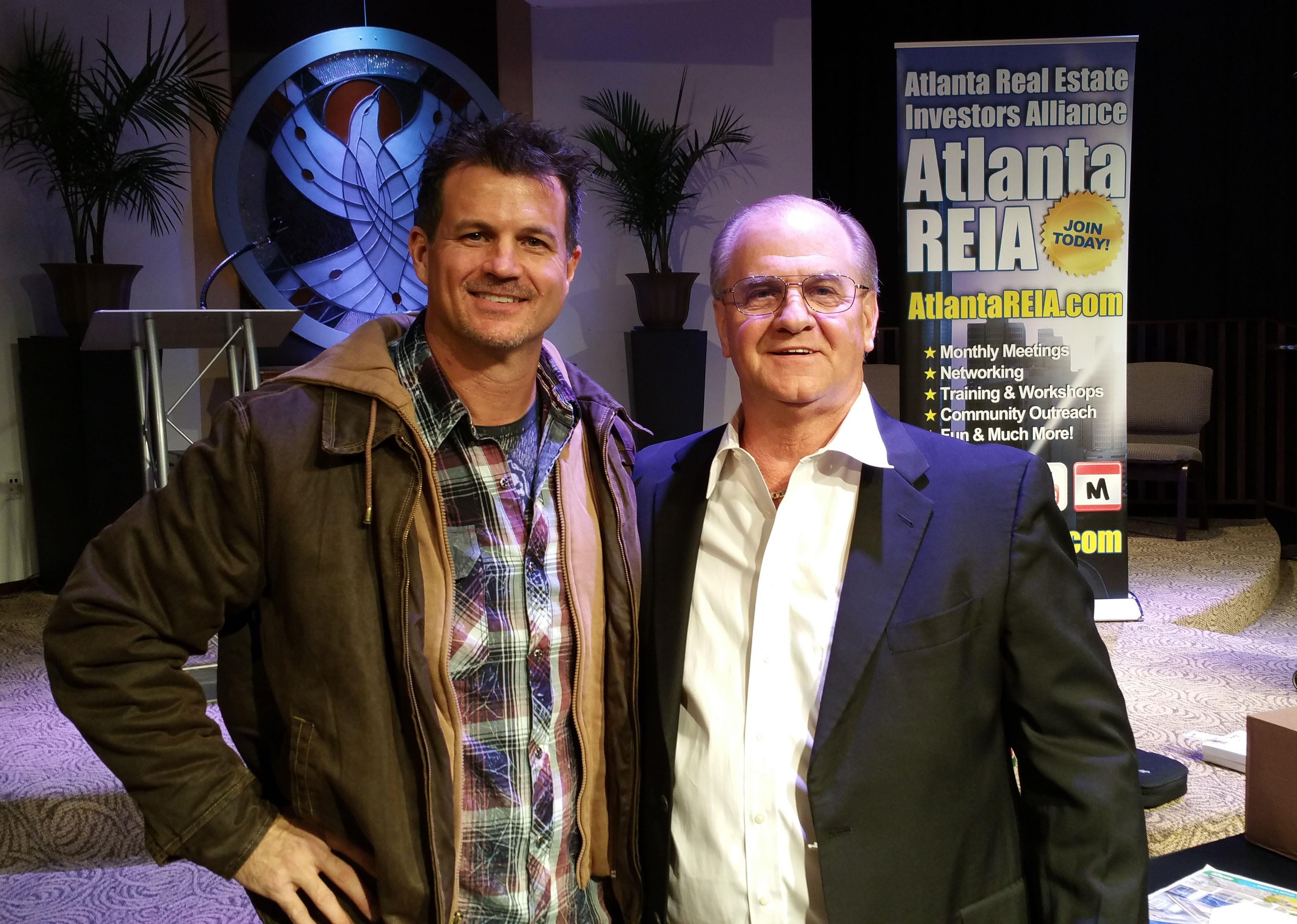 Two men stand together at an Atlanta real estate event, engaging in networking and sharing insights.