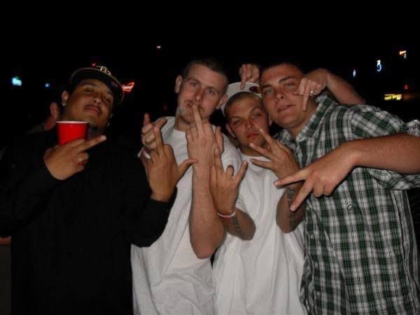 Four friends pose playfully with hand signs while enjoying a night out together.