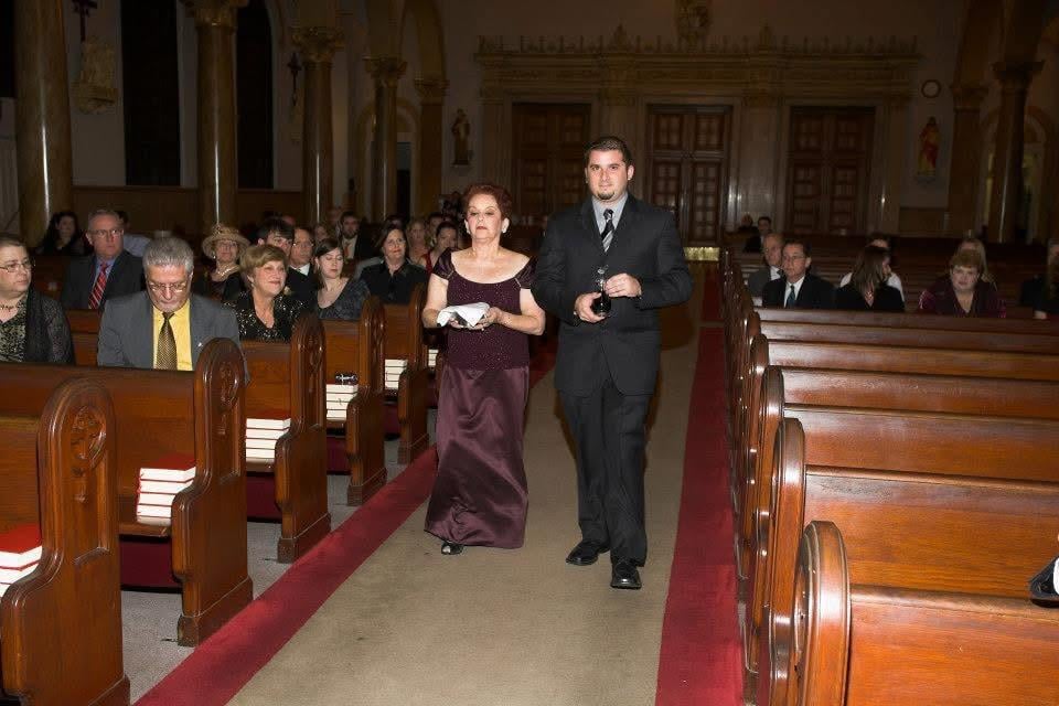 Men and women in formal attire gather in a church, seated in wooden pews for a special occasion.