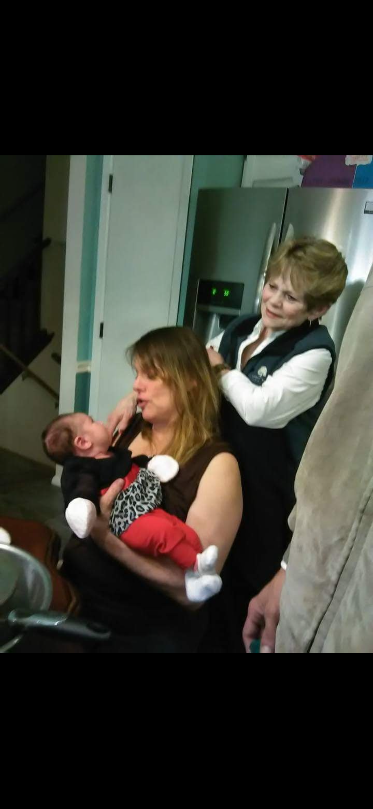 A warm family moment unfolds as a mother holds her baby while relatives share in the joy.