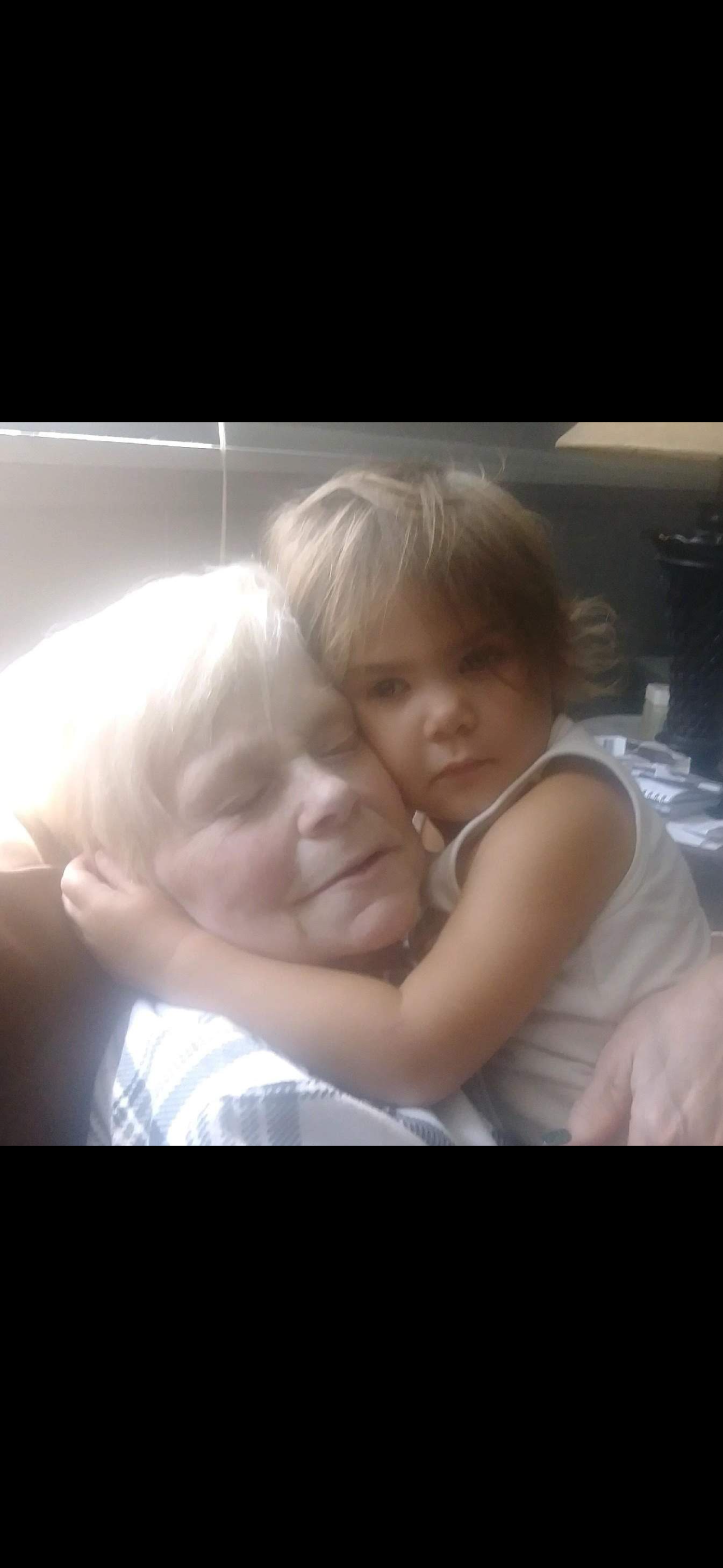 Grandmother shares a tender embrace with her young granddaughter in a cozy setting filled with love.