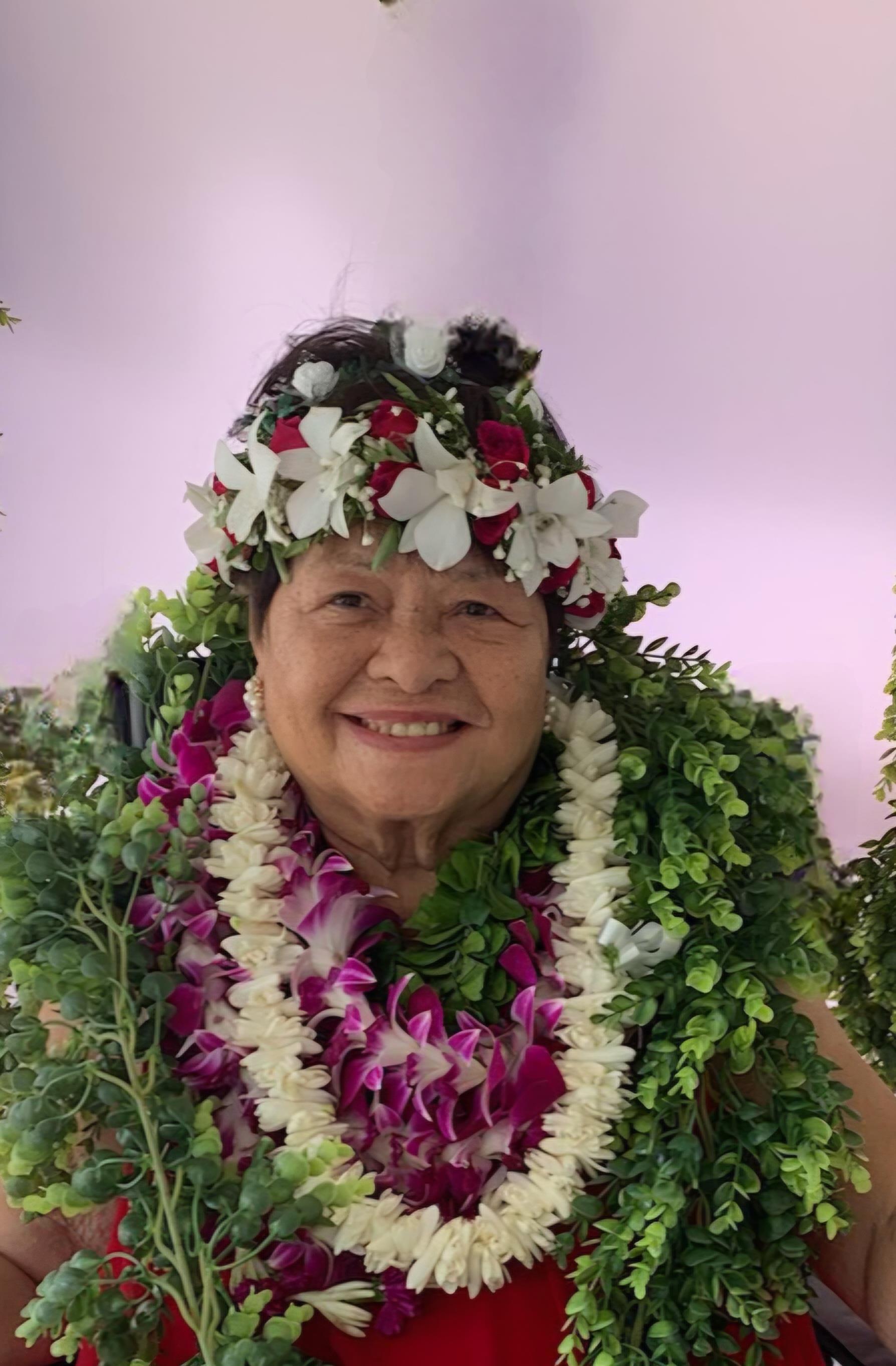 A woman smiles joyfully while wearing multiple flower garlands at a festive event.