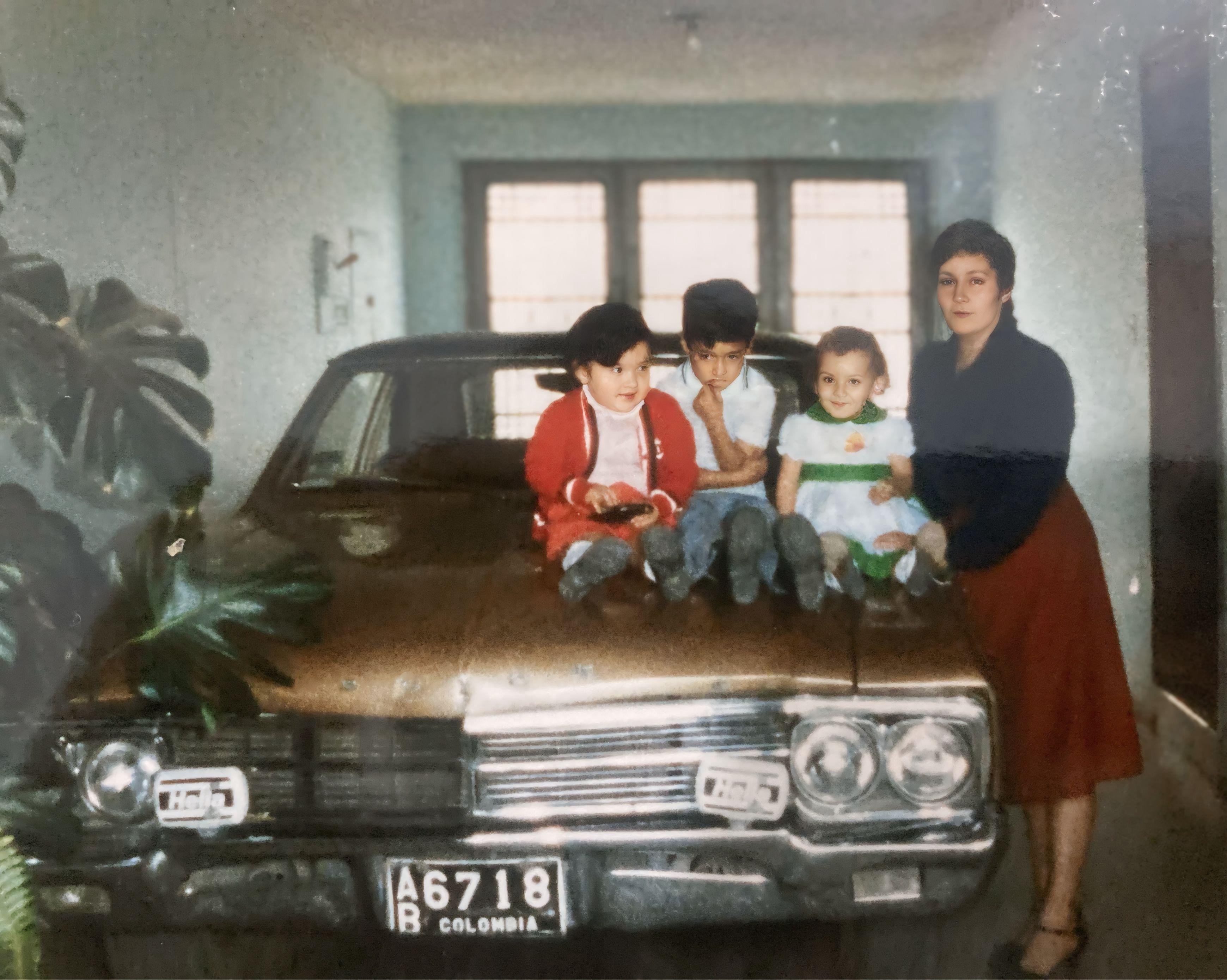 Four children and one woman pose happily on an old vehicle in a cozy interior setting.