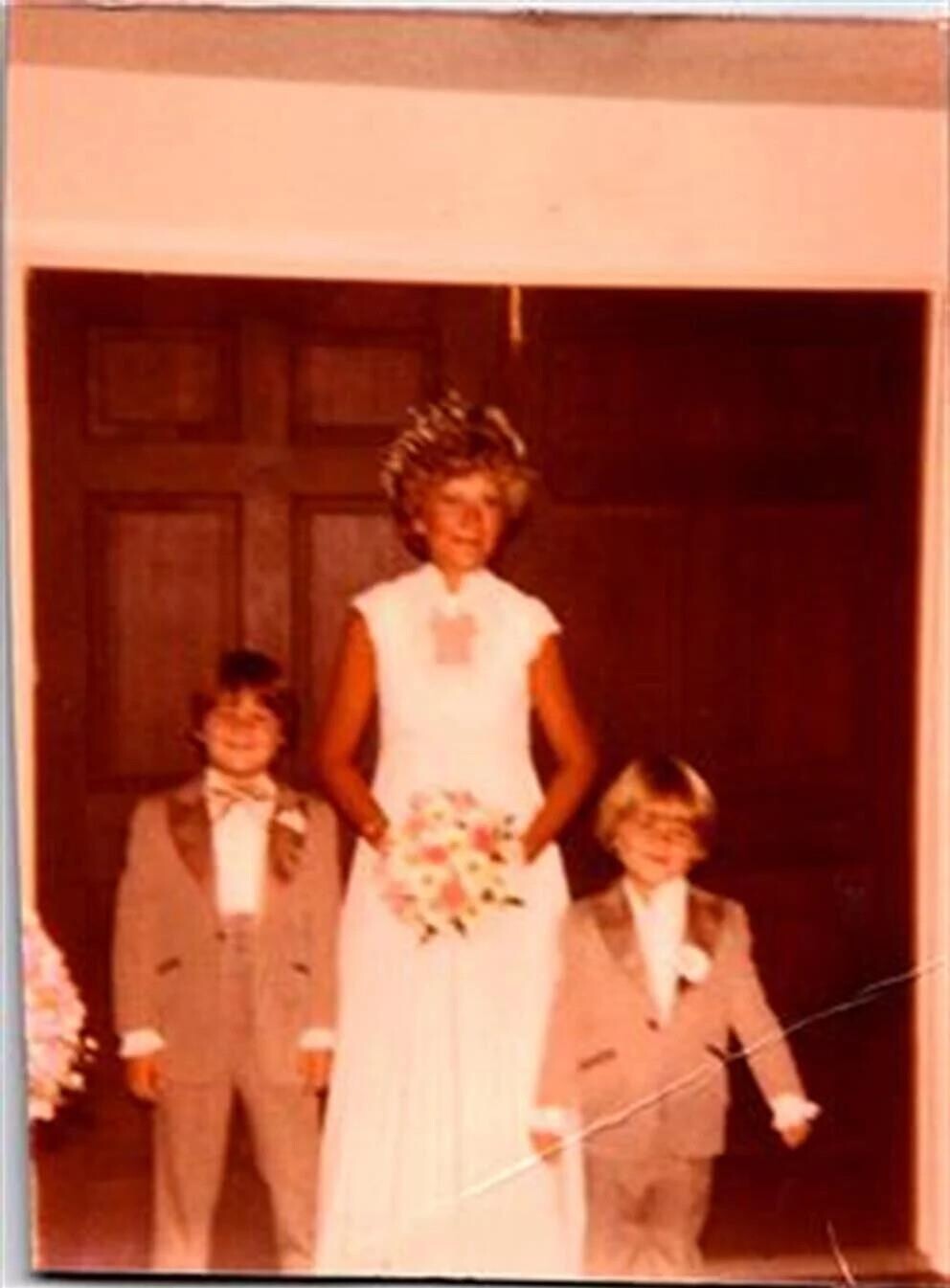 A woman in a white dress with a group of children in a doorway