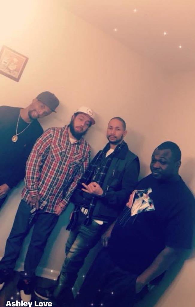 Four friends stand together, smiling and enjoying each other's company in a cozy space.