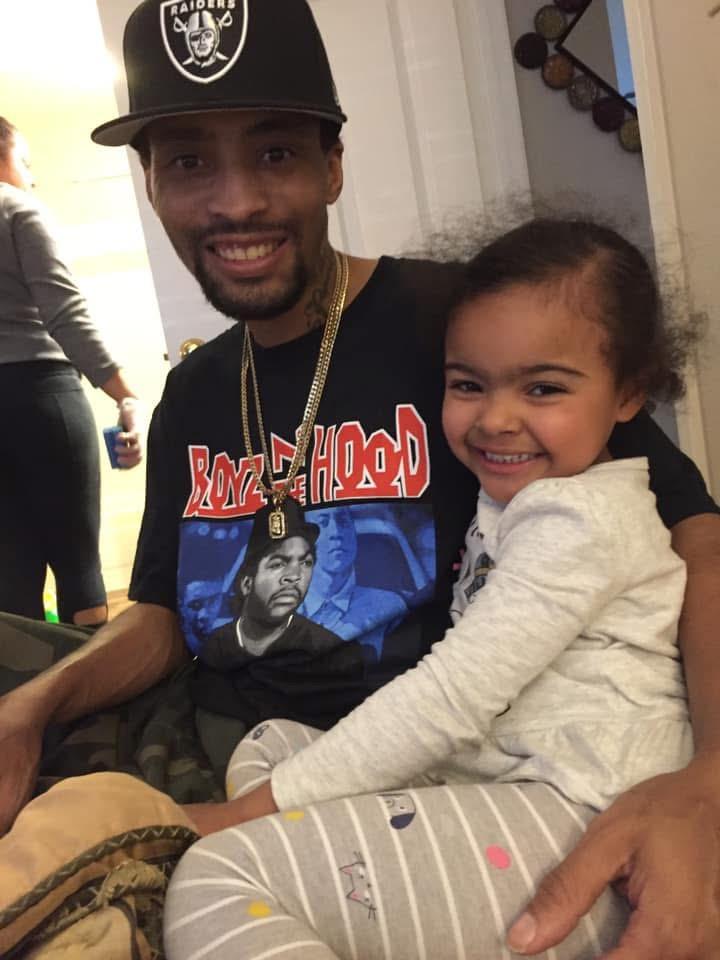 Father and daughter enjoy a happy moment together while family members socialize in the background.