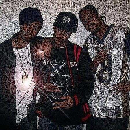 Three casually dressed men stand together, exuding a relaxed, stylish vibe indoors.