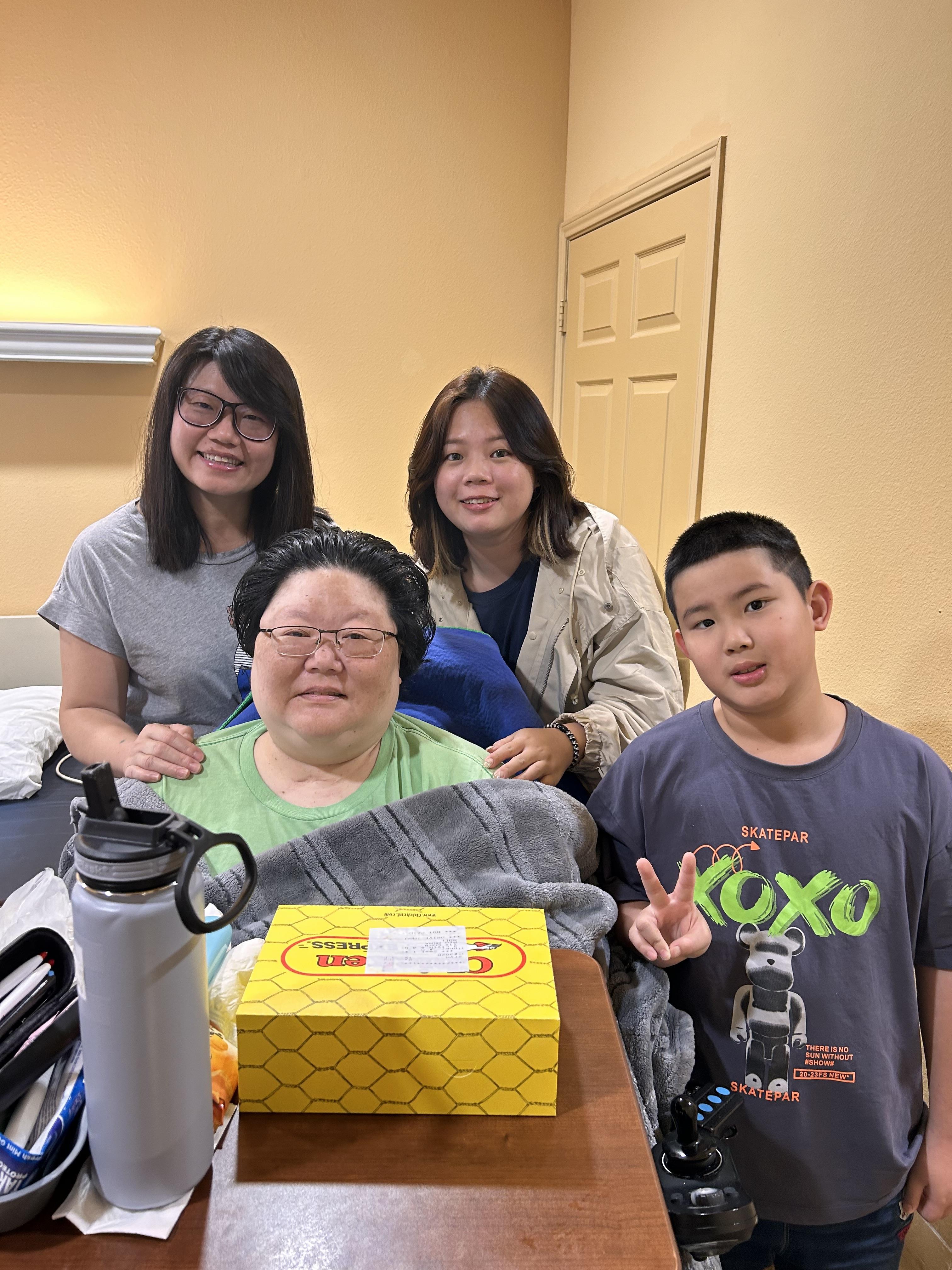 Four family members share smiles and support in a healthcare facility as they visit a loved one.