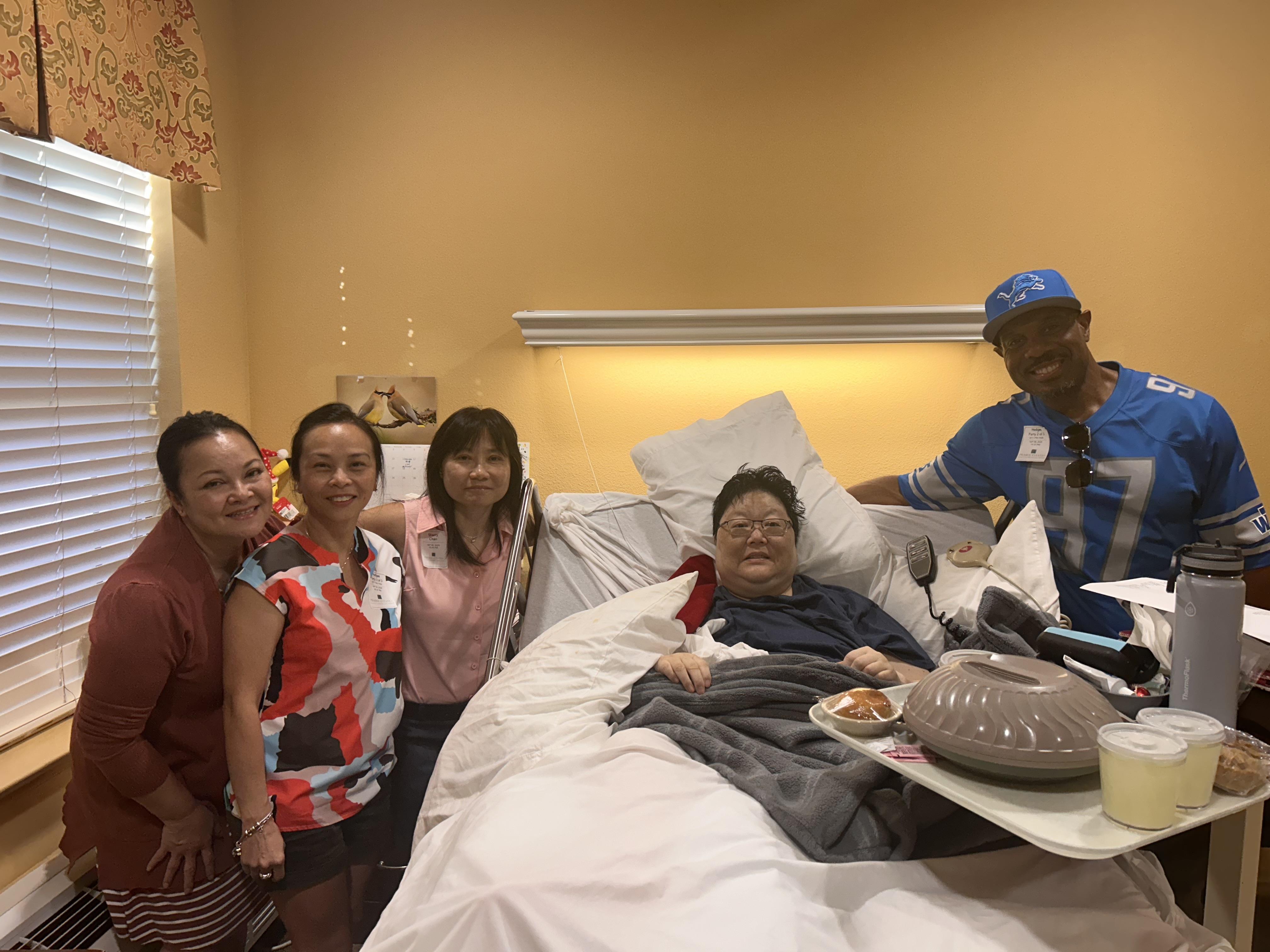 Friends and family share a heartfelt visit with a loved one in a healthcare facility during the day.