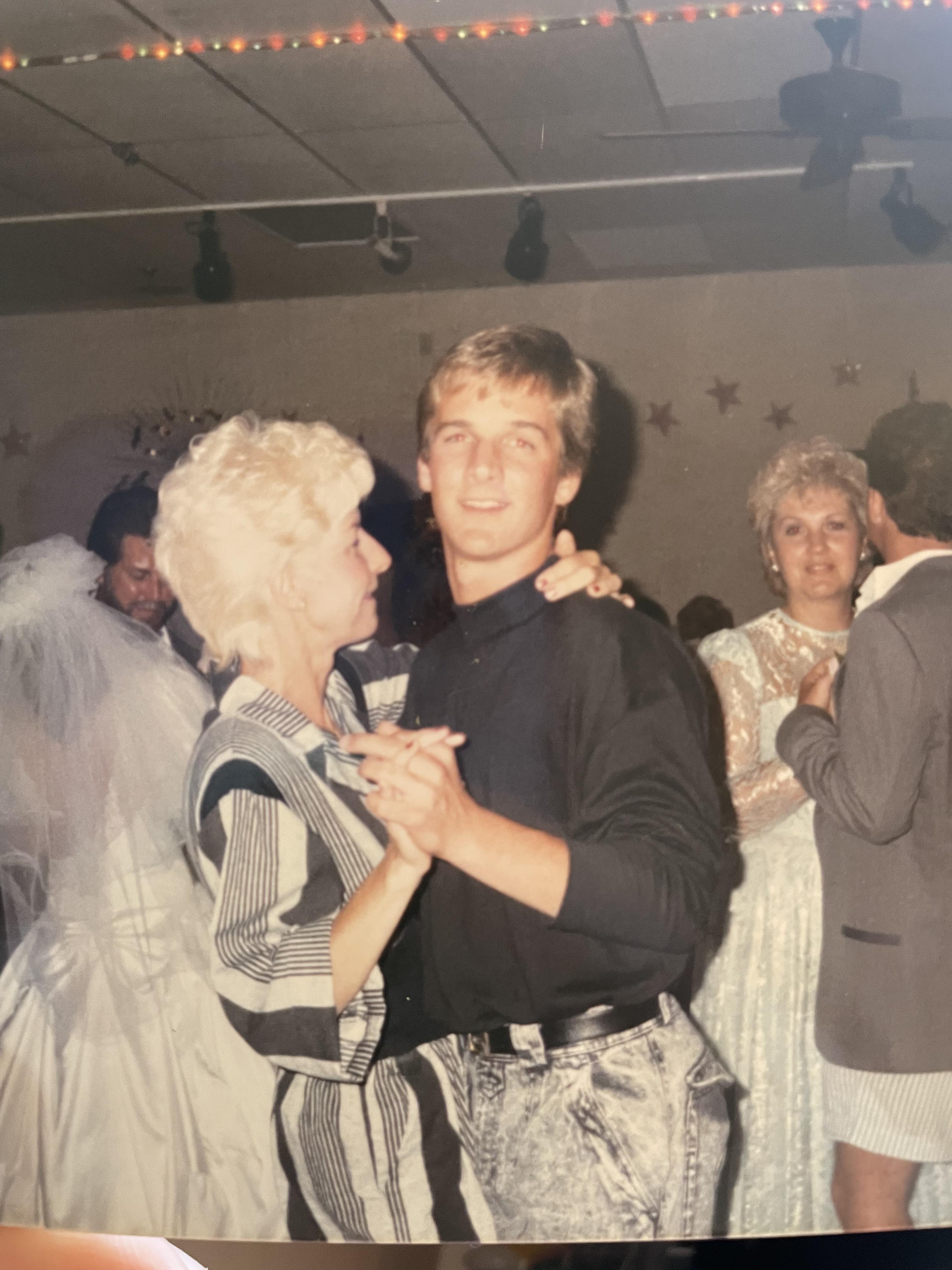 A man and a woman enjoy dancing together amidst joyful attendees in a lively setting.