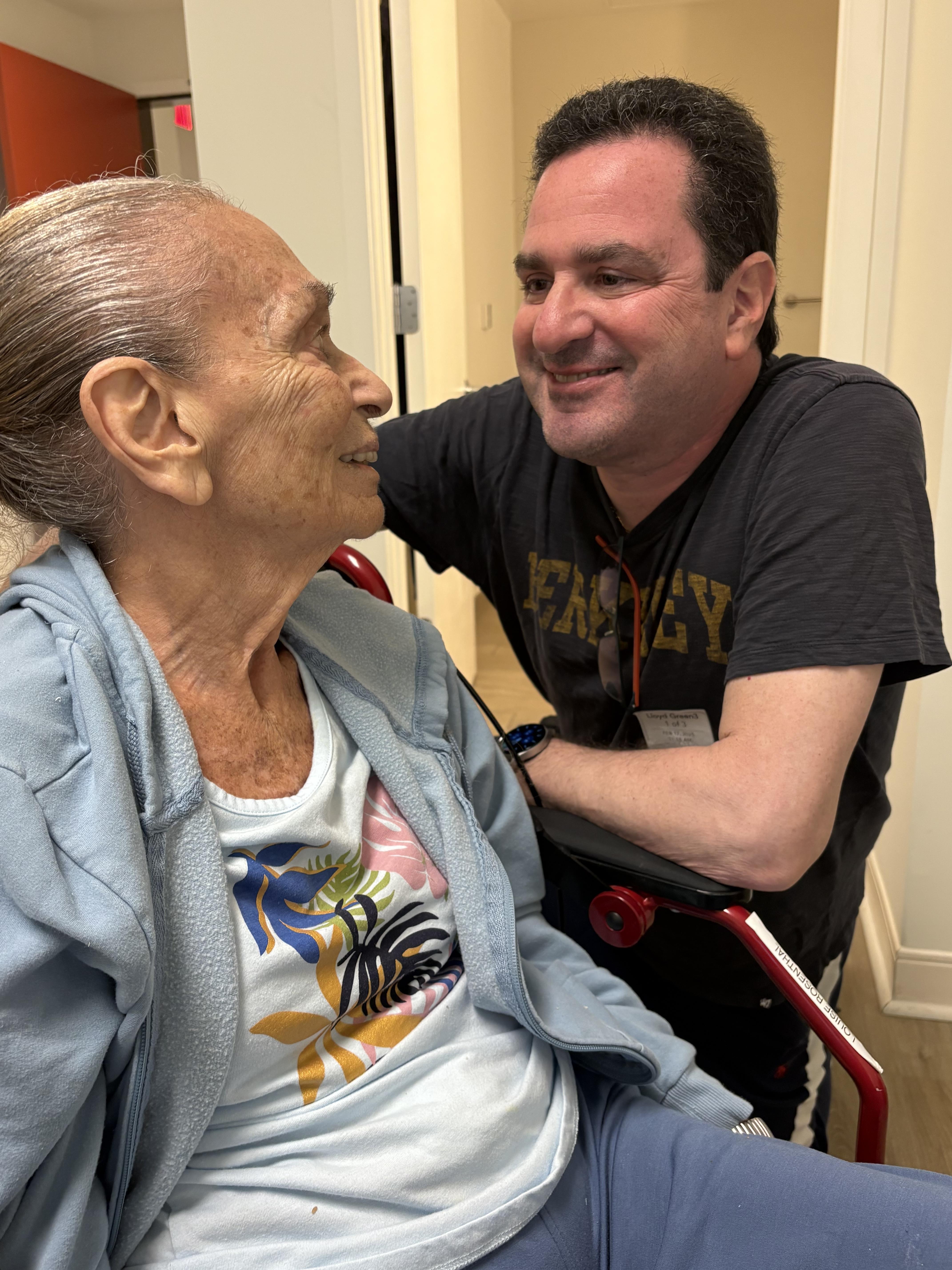 A man shares a joyful moment with an elderly woman in a cozy indoor environment.
