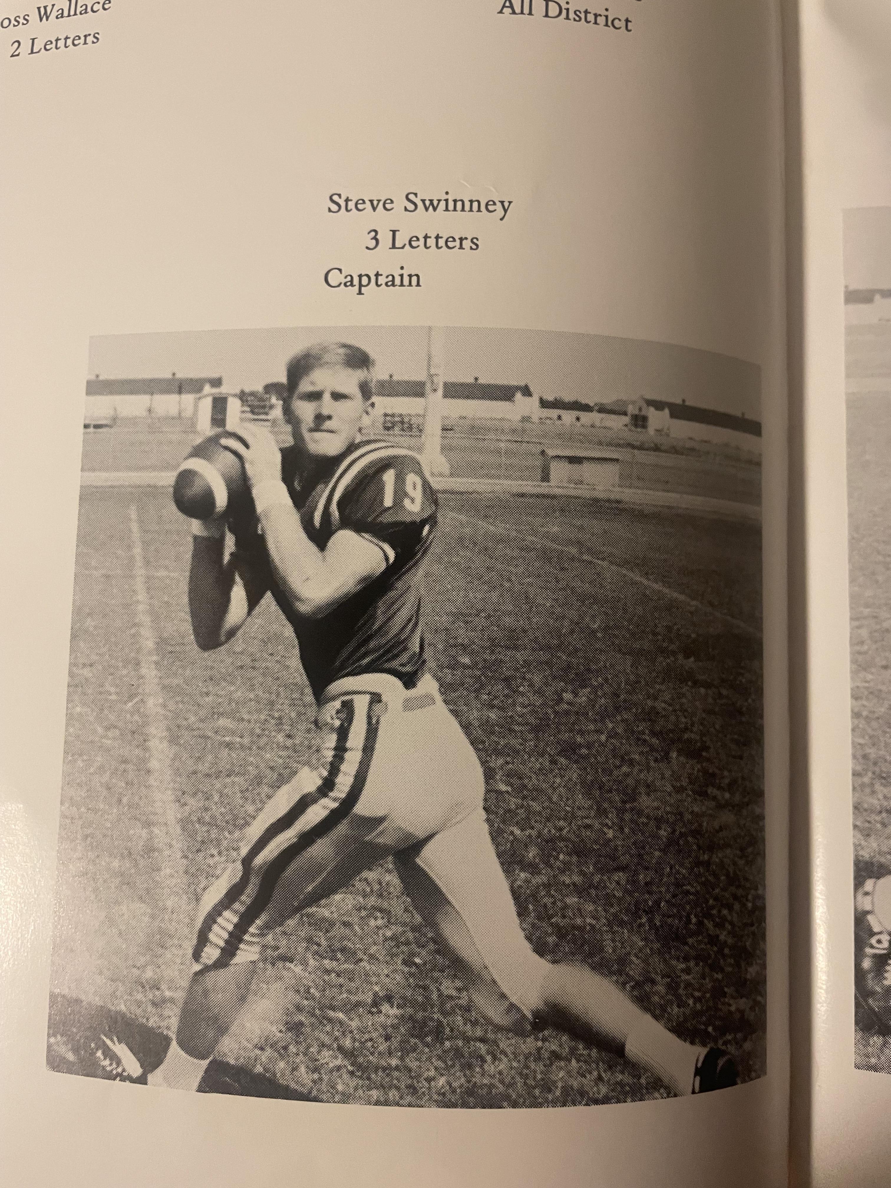 A young athlete in a football uniform stands poised to pass on a sunny field.