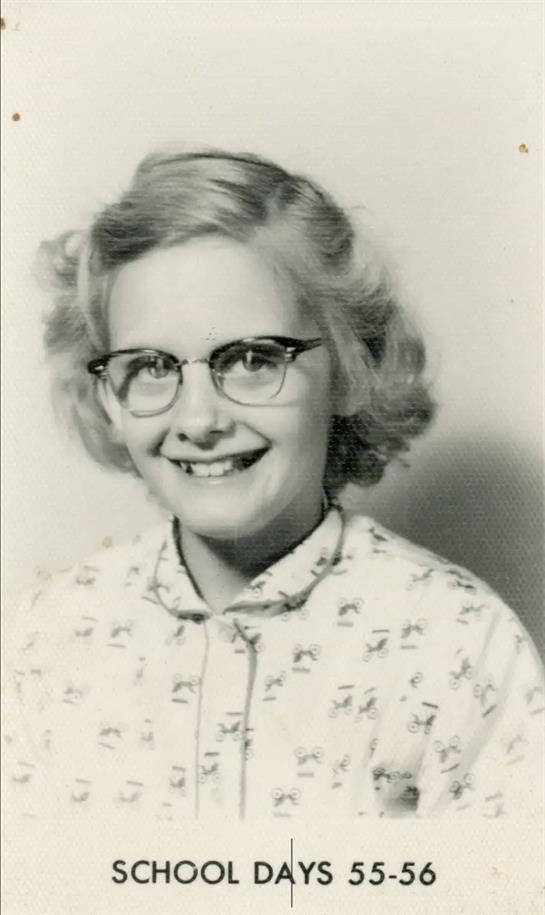 A woman wearing glasses and smiling
