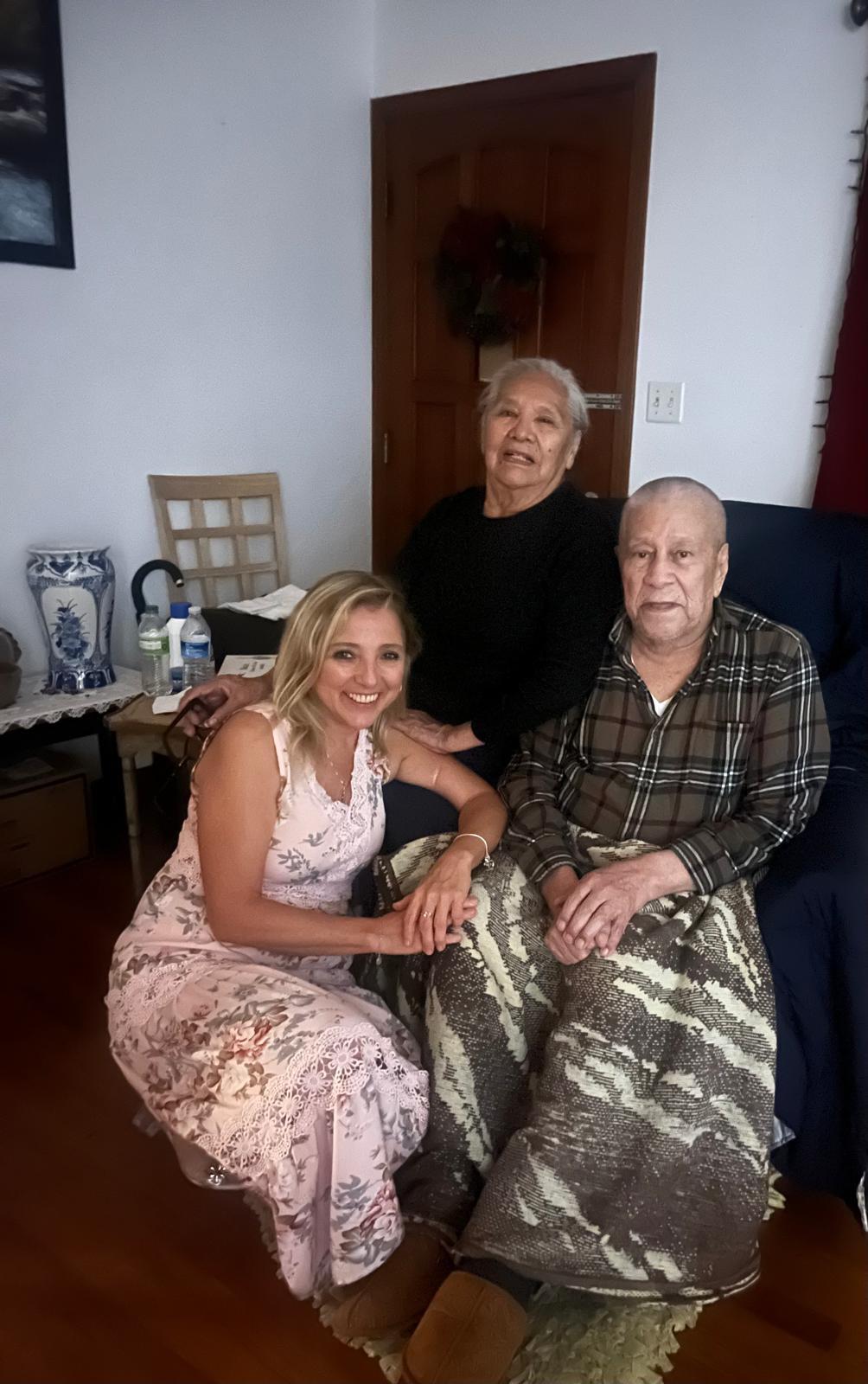 Three family members share a warm moment in a cozy living room, enjoying each other's company.