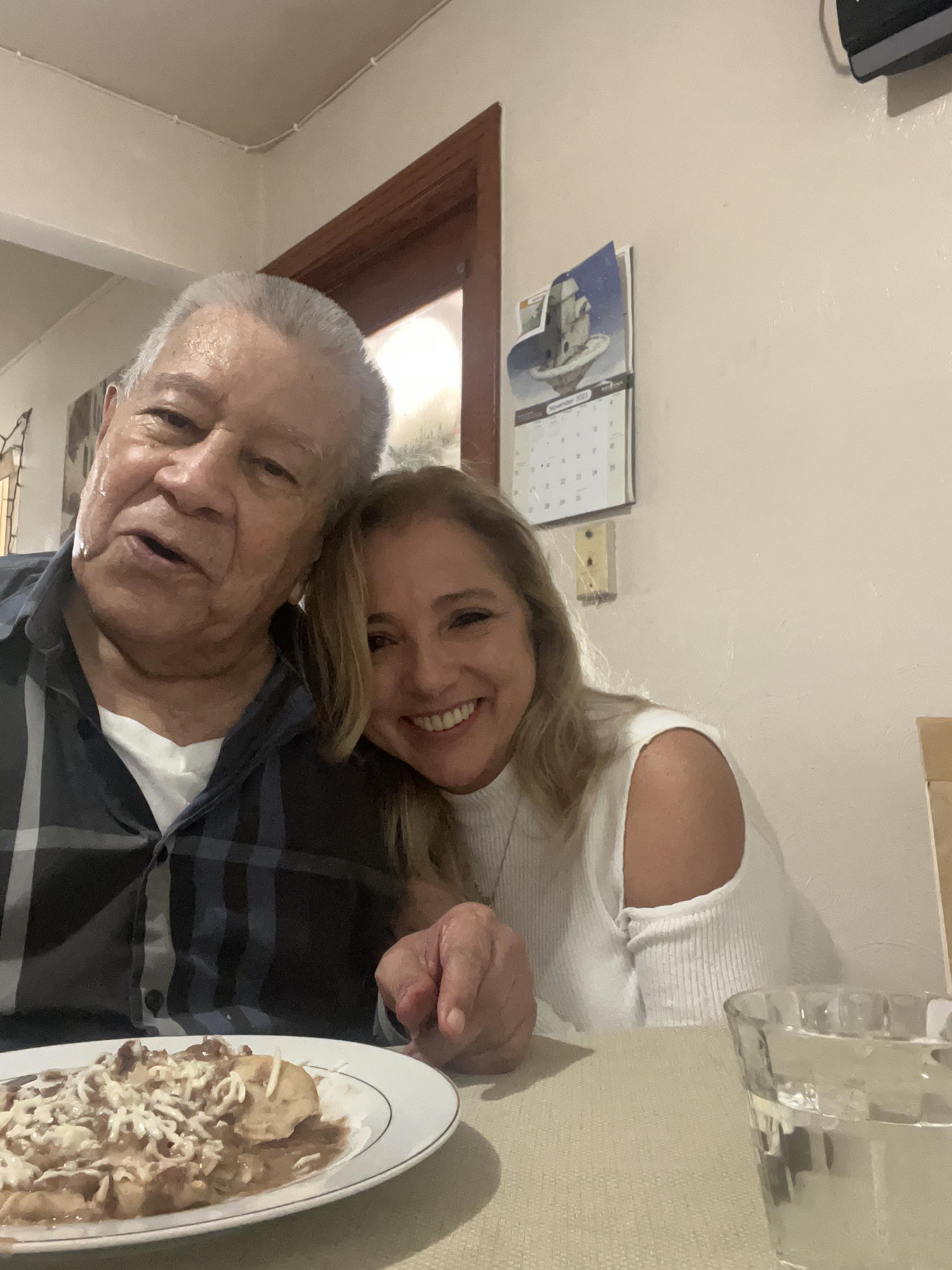 Two people share a cheerful moment while enjoying a meal in a warm, inviting home environment.