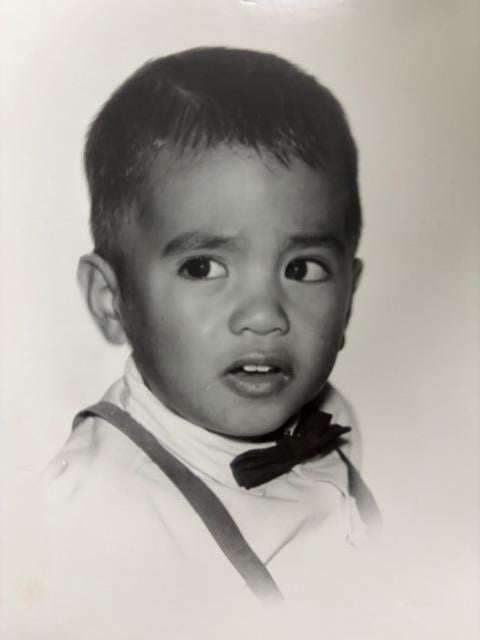 Child in formal wear displays a curious expression while posing for a picture at an event.
