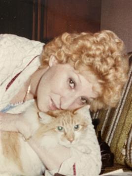 Woman with curly hair affectionately holds an orange cat close in a cozy indoor space.