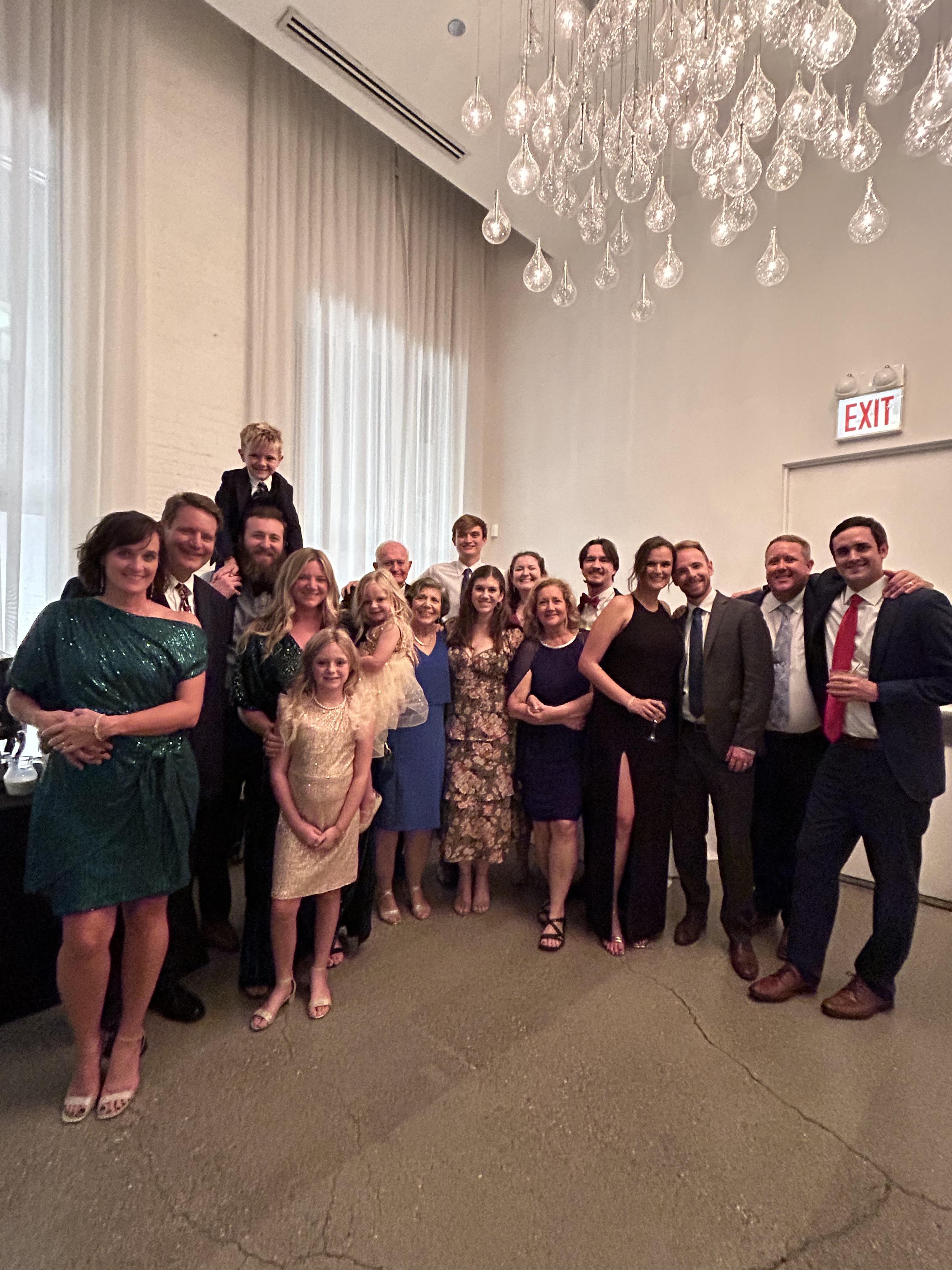 A large group of family and friends poses together in a stylish location, full of happiness.