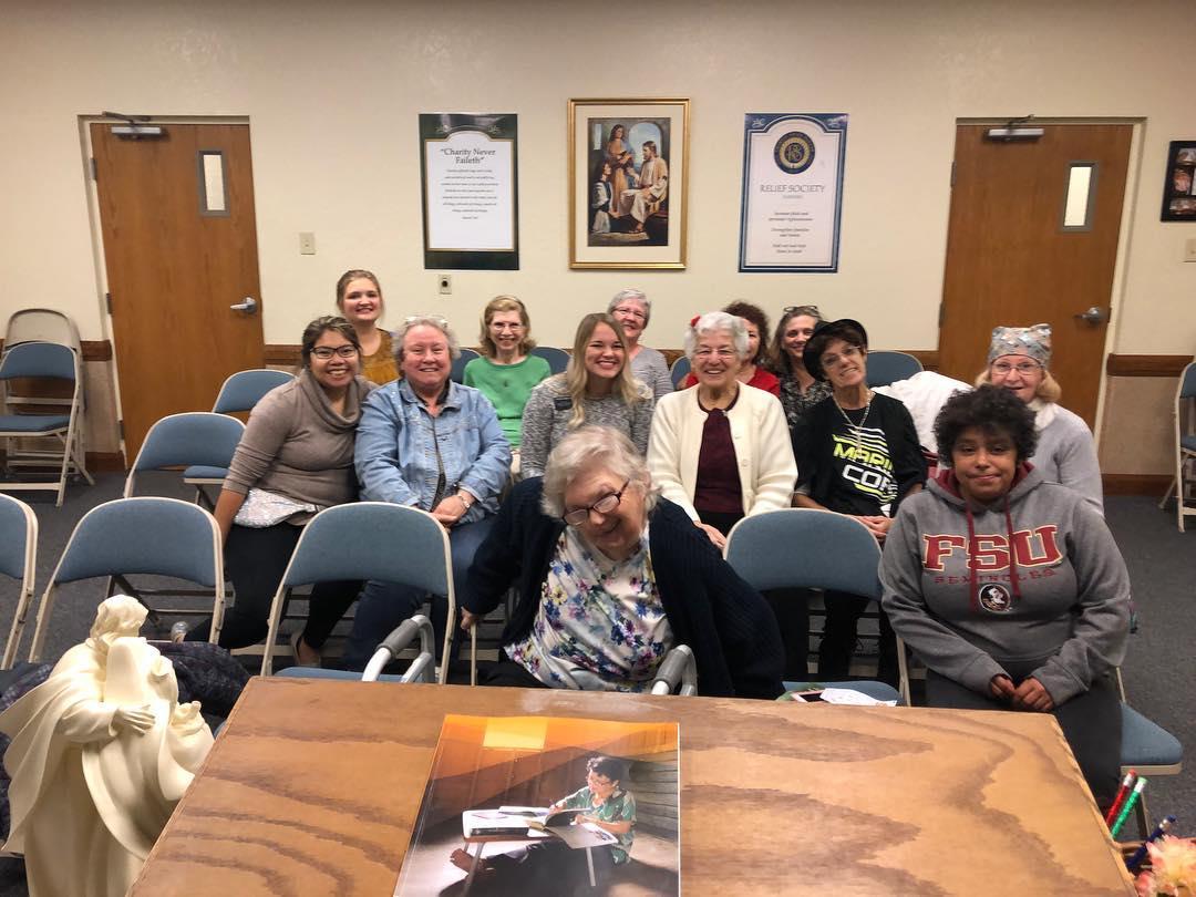 A lively gathering of women sharing smiles and stories at a community meeting in a welcoming room.