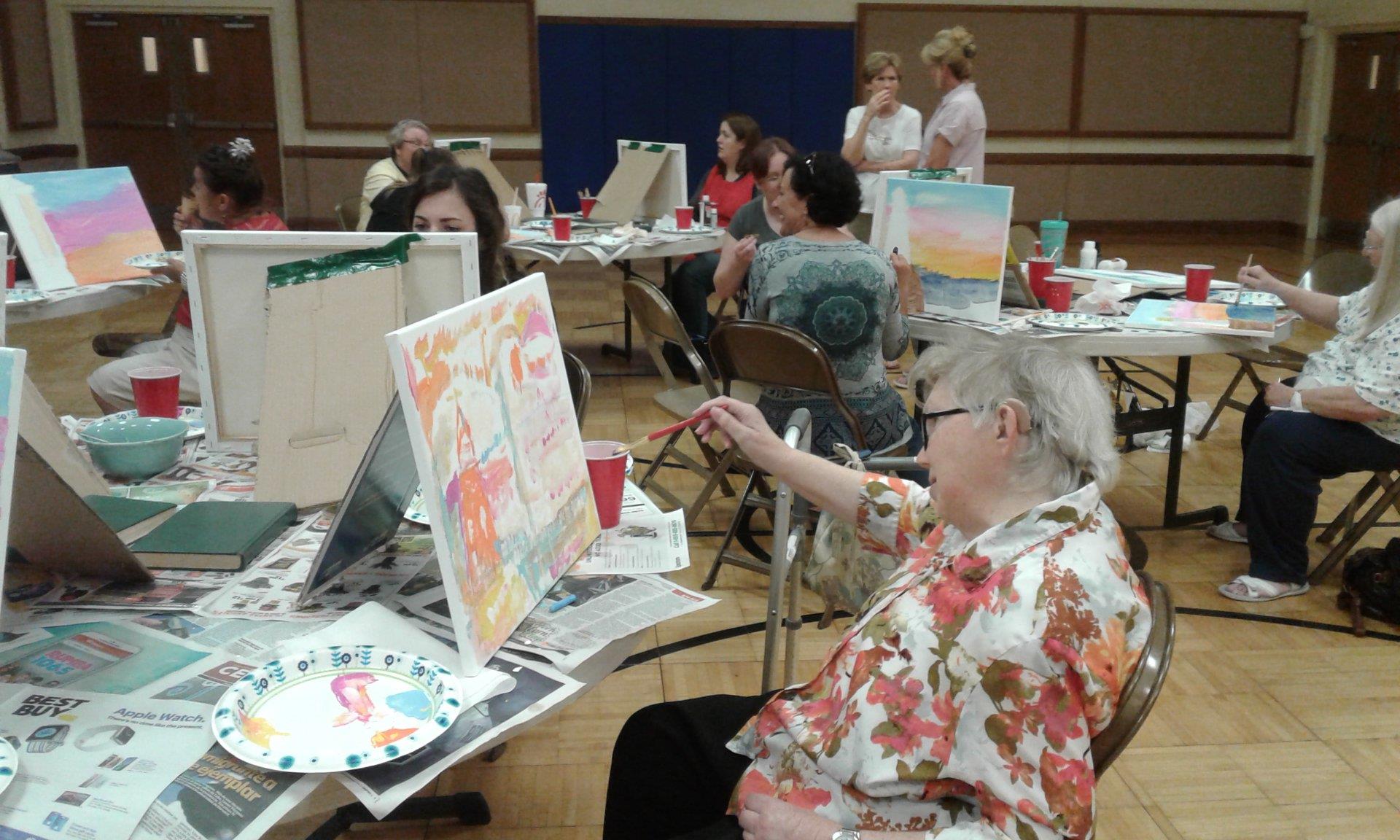 Participants enjoy a creative painting class together in a community hall.