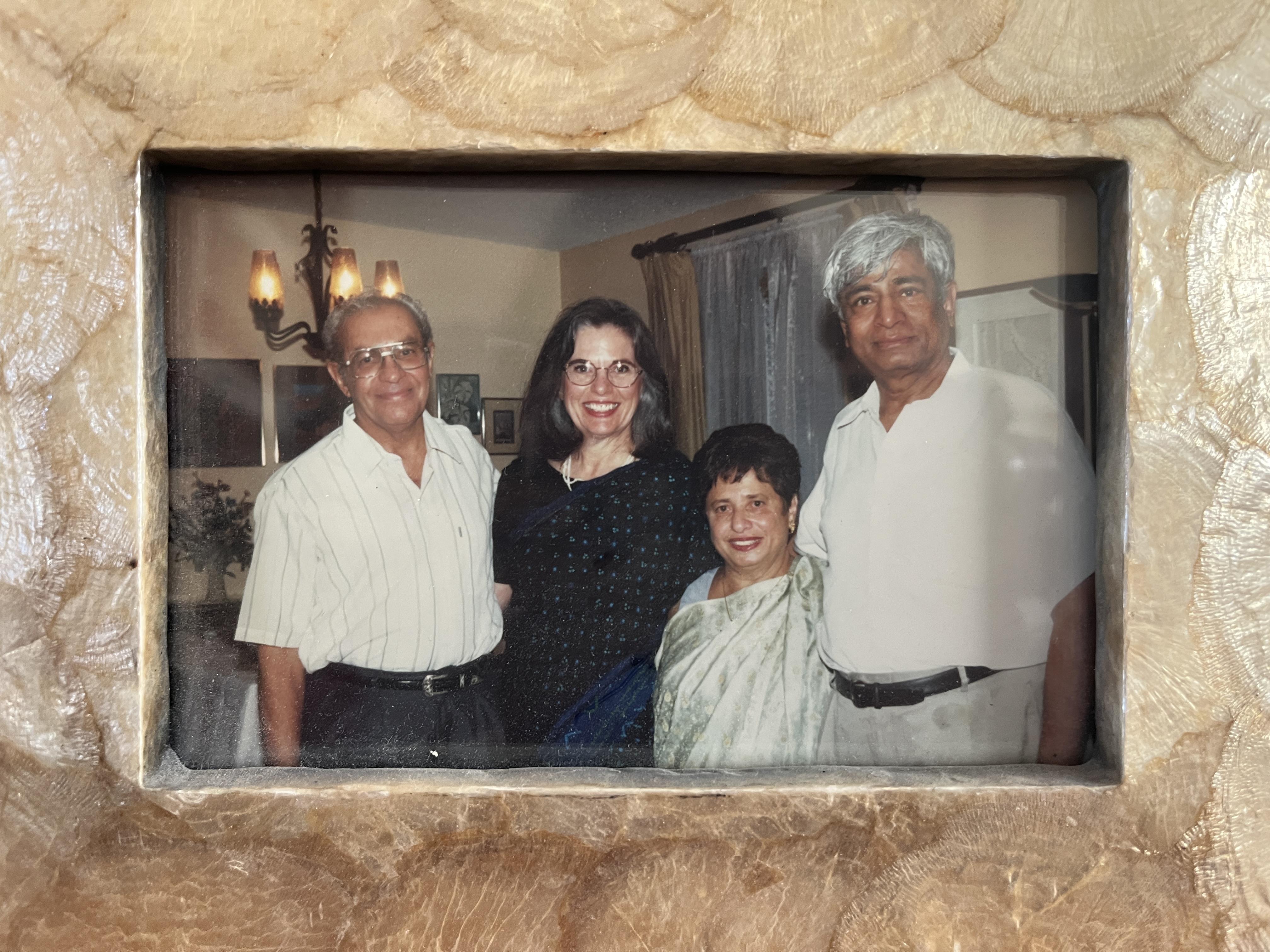 Four friends are posing together in a warm living room, sharing smiles and memories.