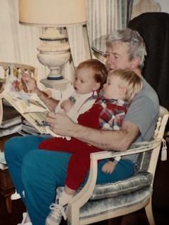 Two kids listen intently as their grandfather reads, emphasizing family bonding time.