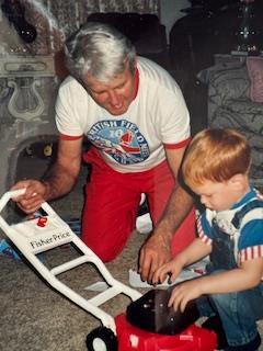 A grandfather shares a joyful moment with his grandson while playing with a toy in their home.