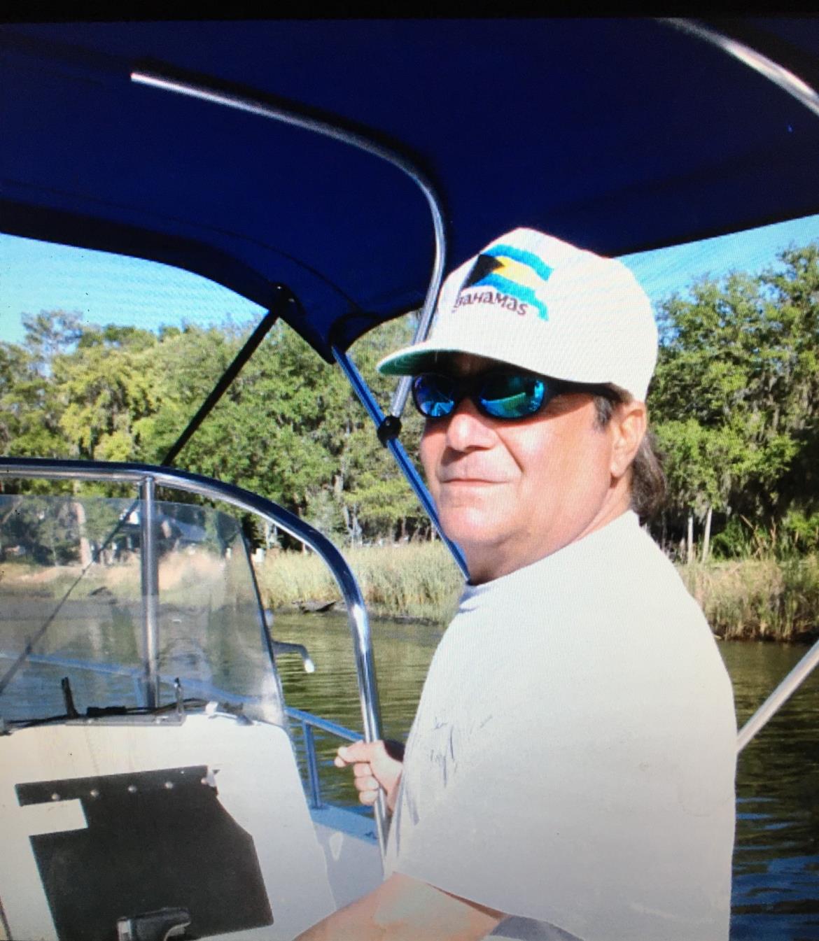 A fisherman enjoys a peaceful day on the river, casting his line while surrounded by greenery.