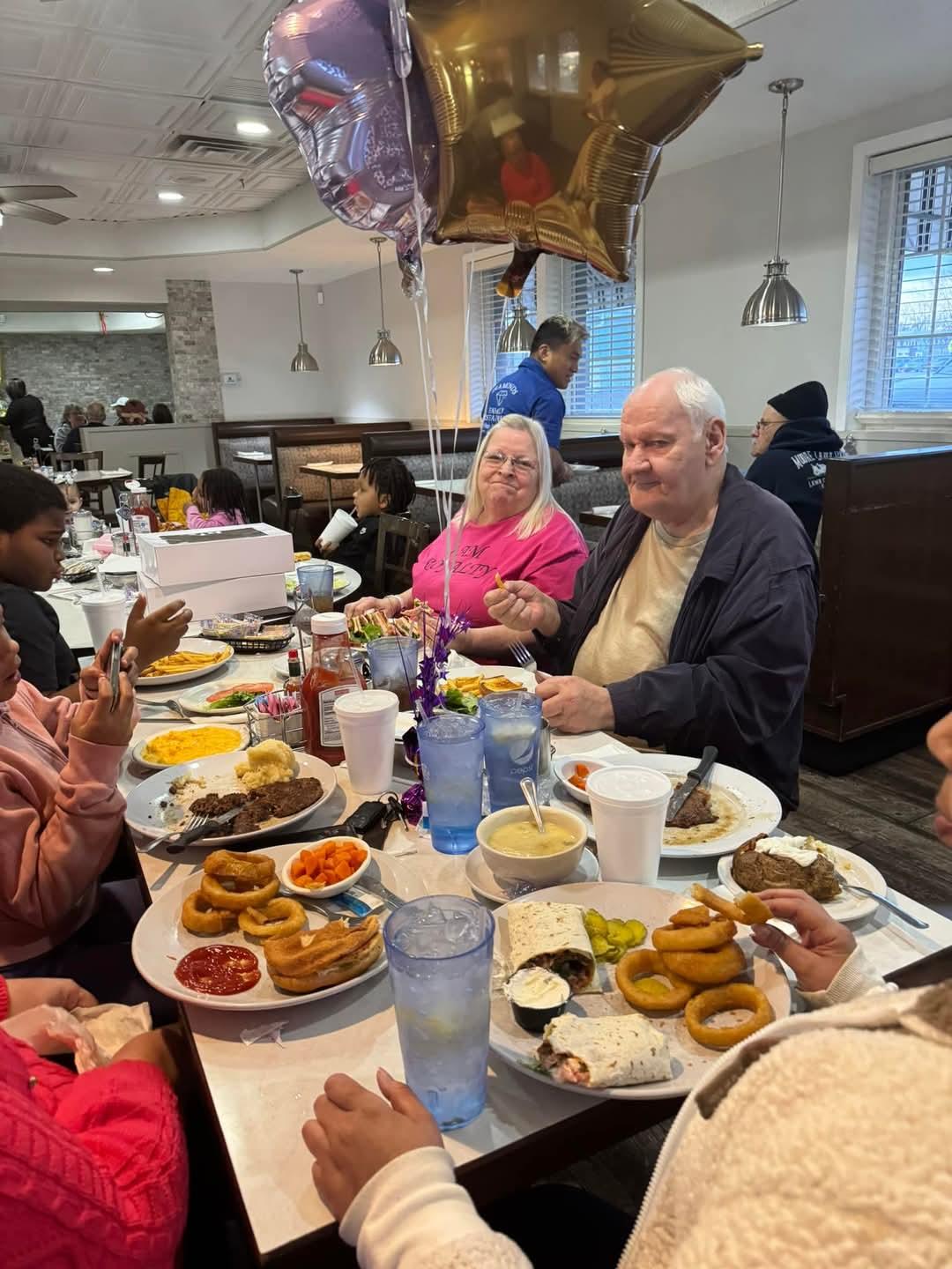 A group of family members share a joyful dinner at a bustling restaurant, celebrating together.