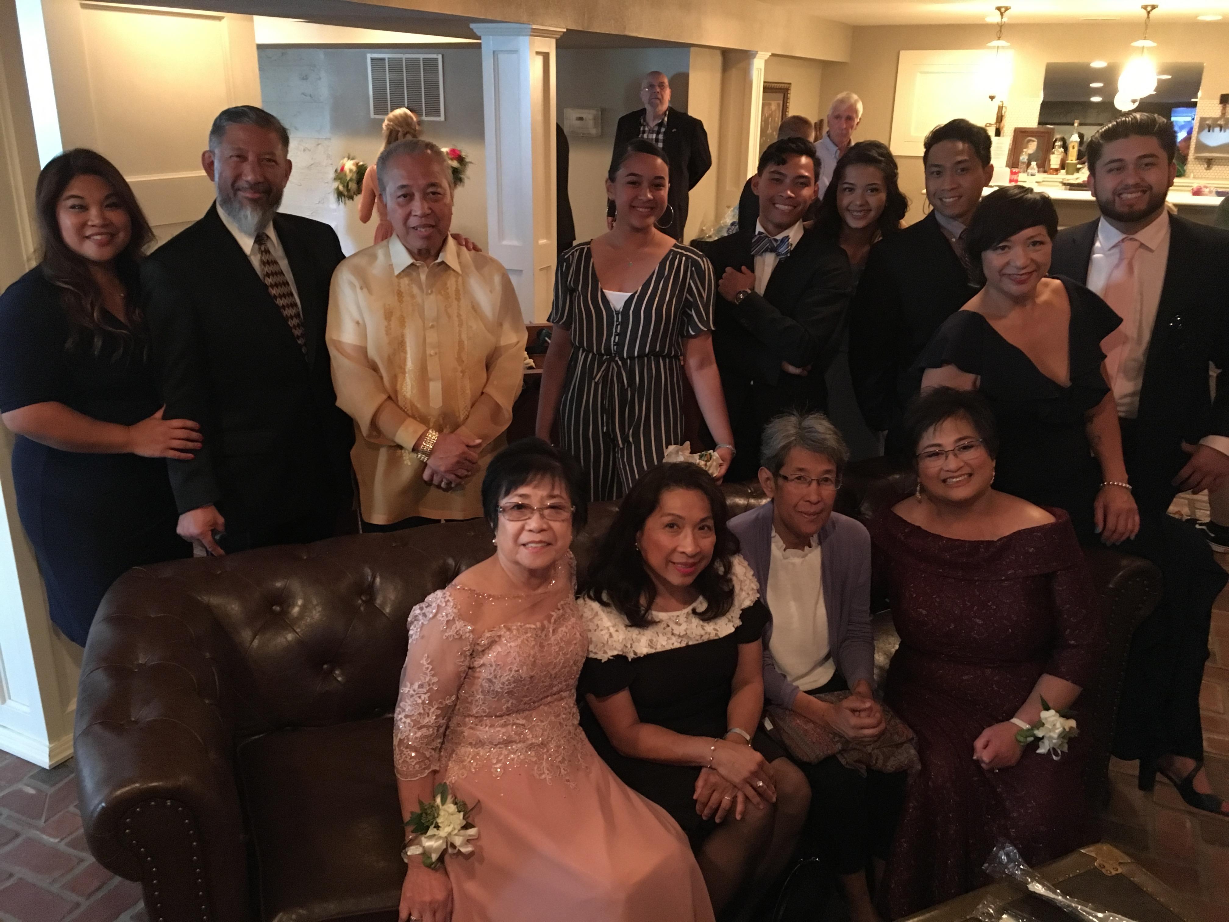 Group of family members dressed in formal attire enjoying a festive gathering in a warm setting.