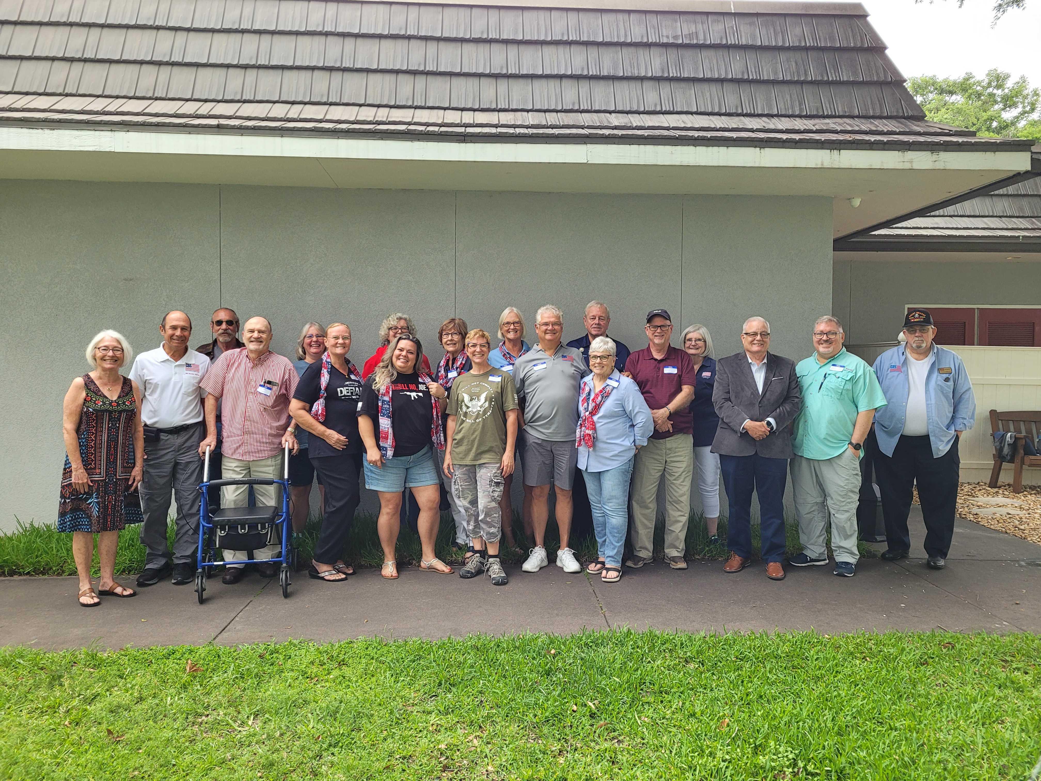 Group of diverse individuals smiling and posing together at a community reunion event outdoors.