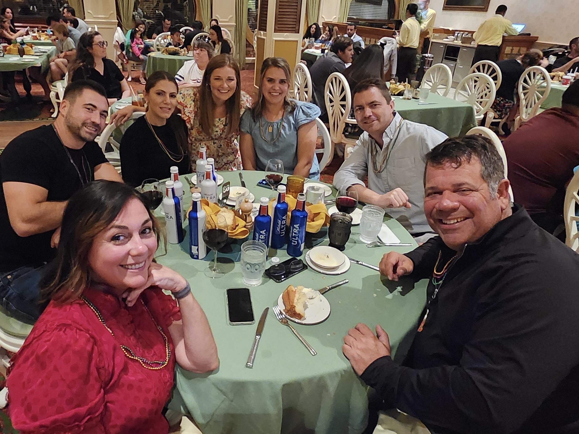 Friends gather around a table, sharing laughter and food in a lively restaurant environment.