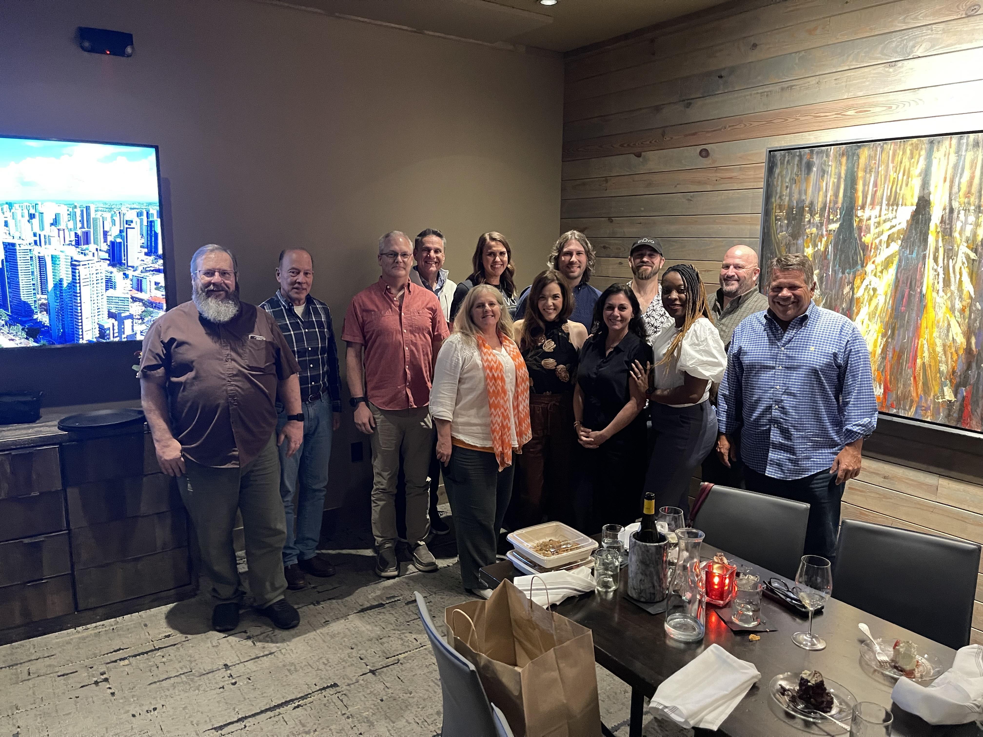 Friends pose together, smiling and enjoying a celebratory dinner at a stylish restaurant.