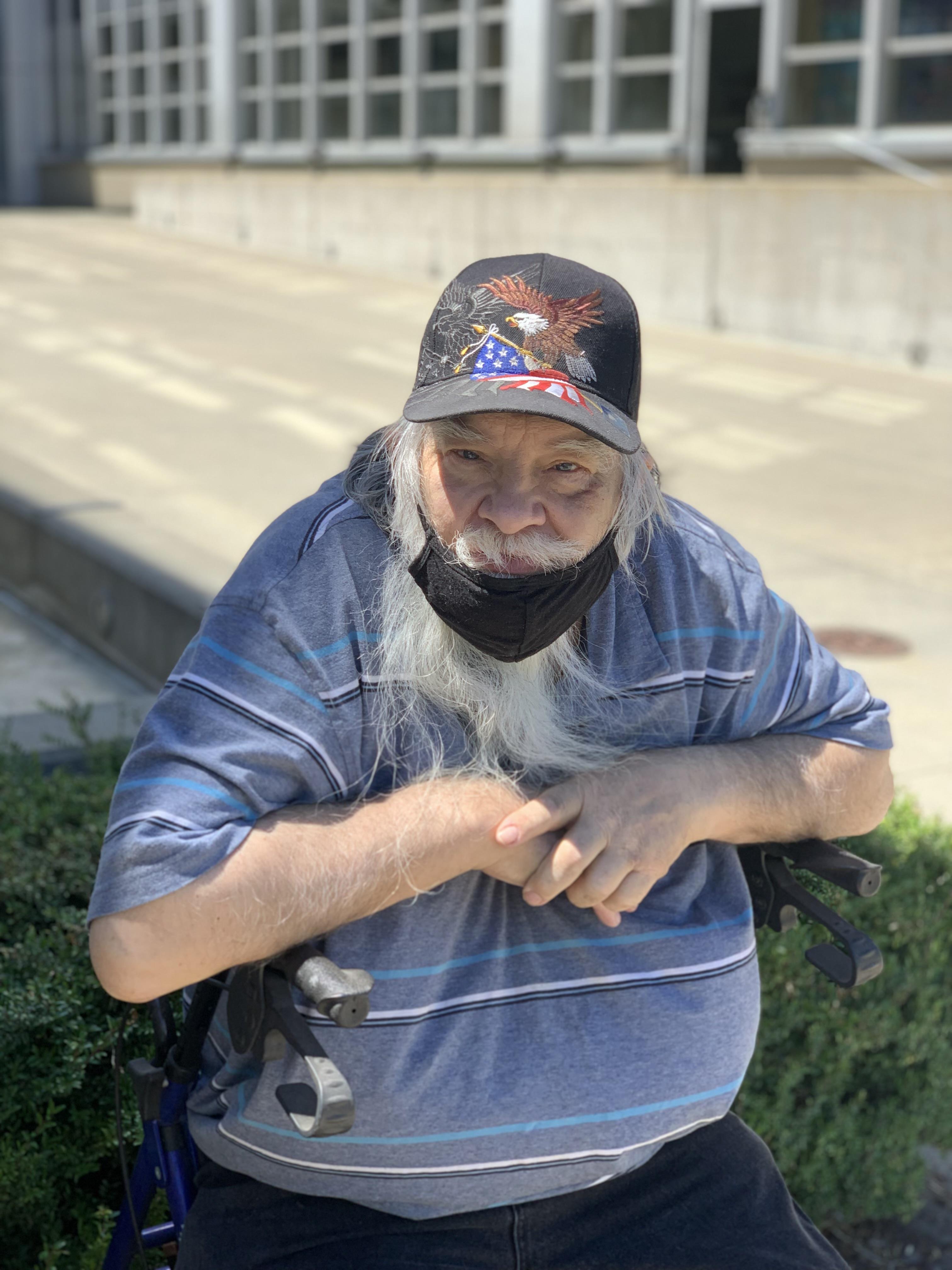 Senior man with a long white beard enjoys the warm sunlight while resting outside.