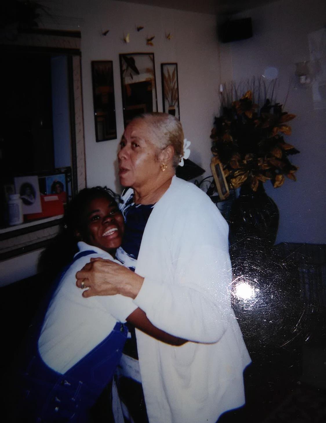 Grandmother and granddaughter embrace joyfully in a warm, inviting living room setting.