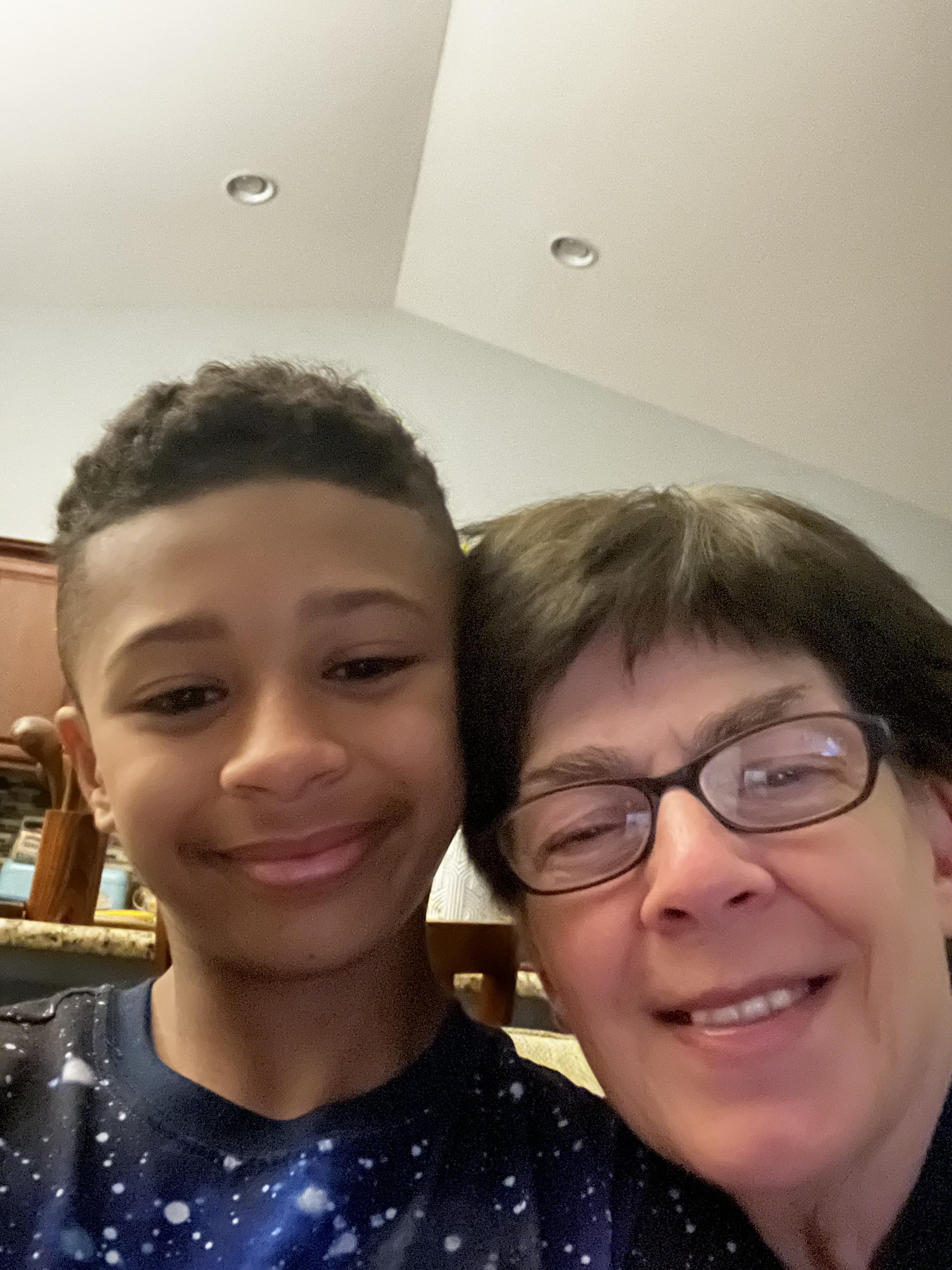 A joyful grandmother and her grandson smile together while relaxing in their cozy living room.