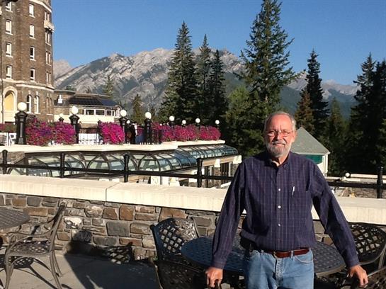 A man standing on a balcony with a mountain in the background